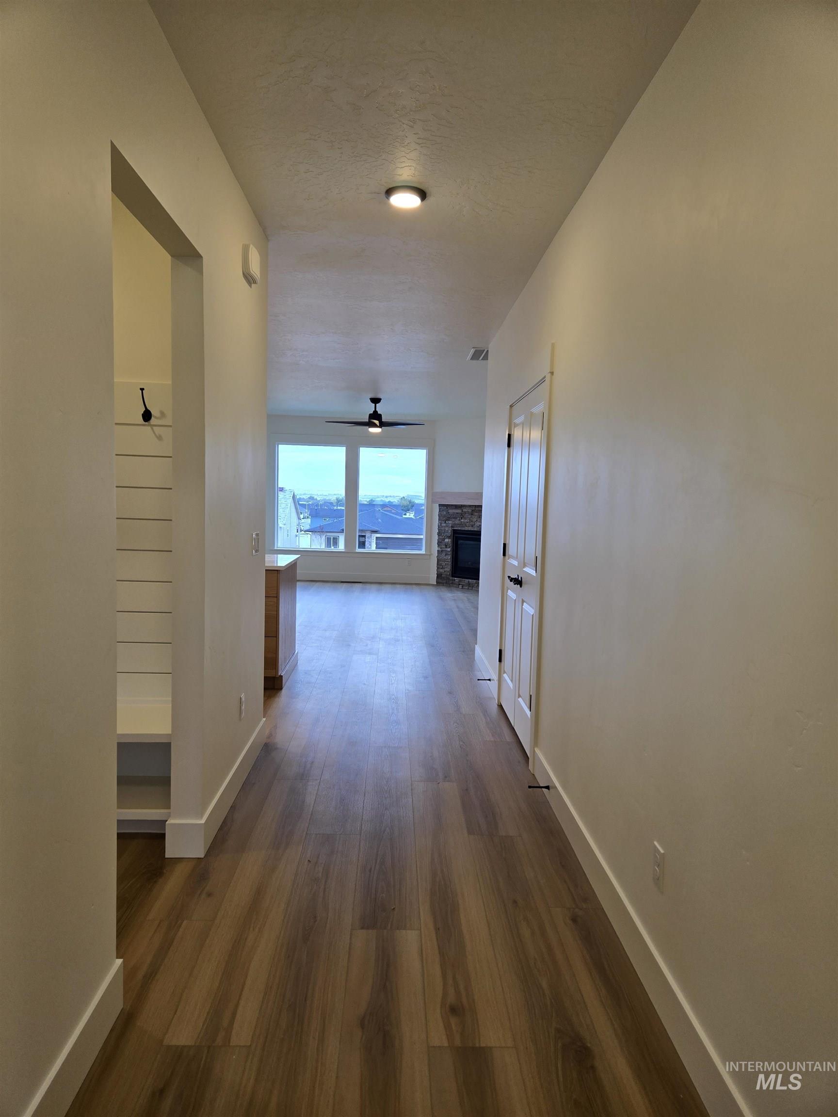Corridor with dark wood-style flooring and baseboards