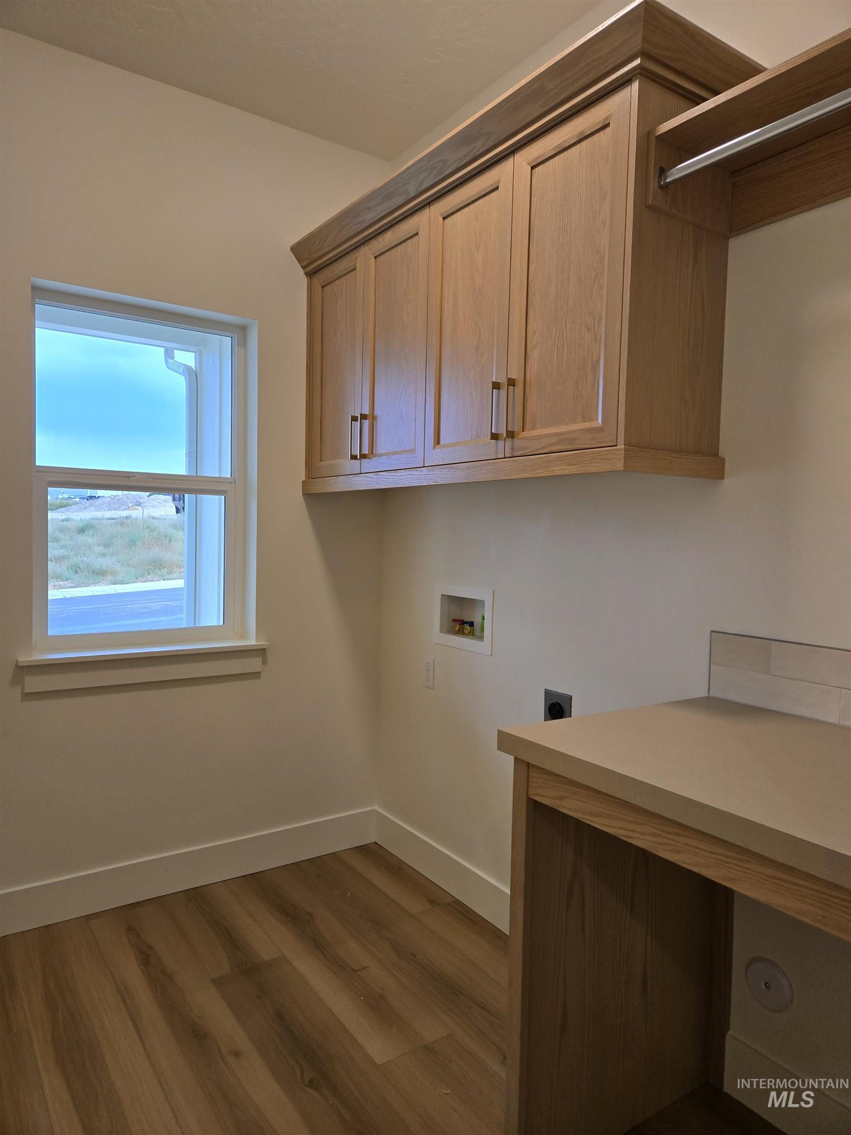 Laundry area with dark wood finished floors, washer hookup, electric dryer hookup, and a desk