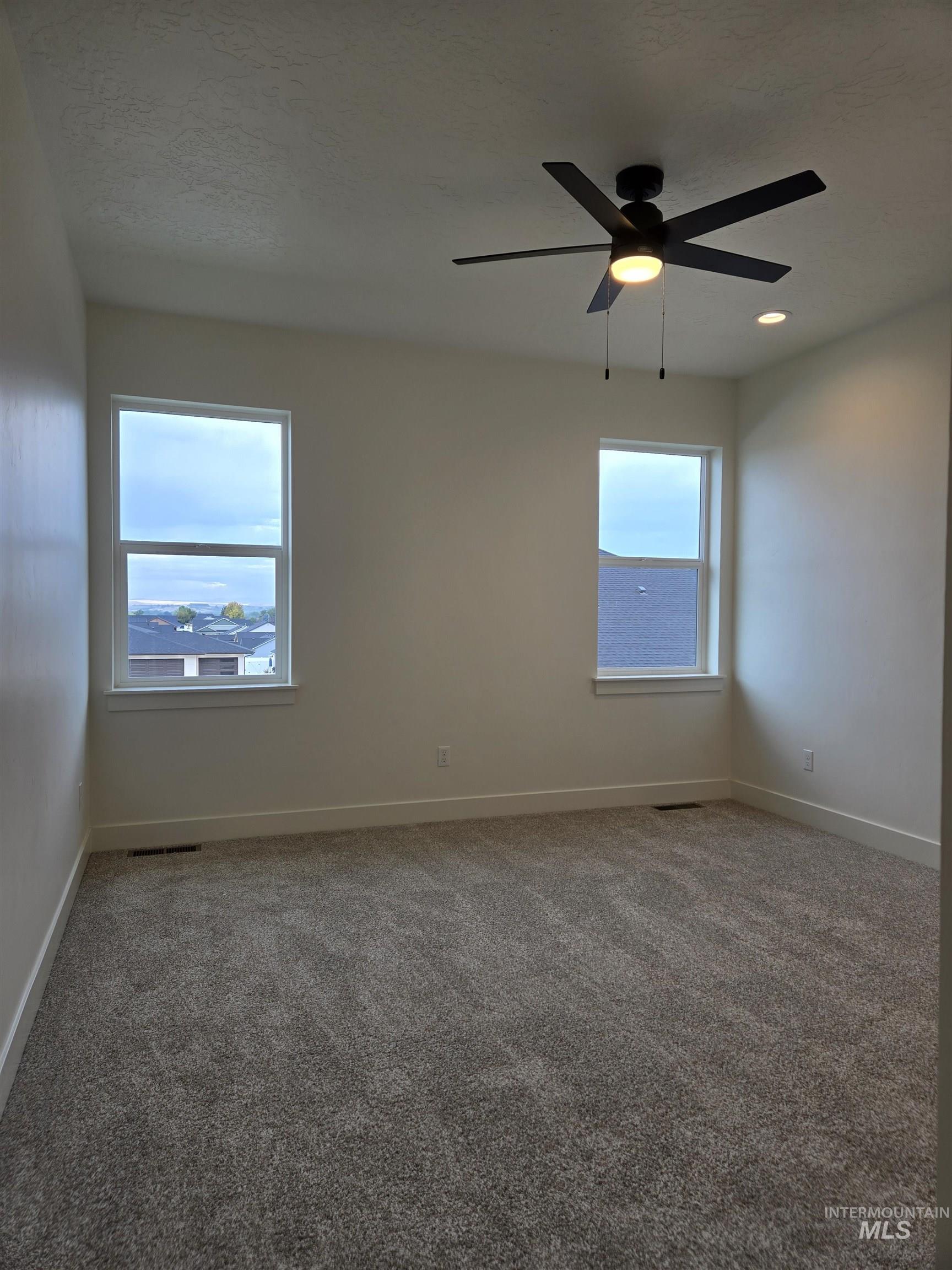 Empty room featuring carpet flooring, ceiling fan, and a textured ceiling