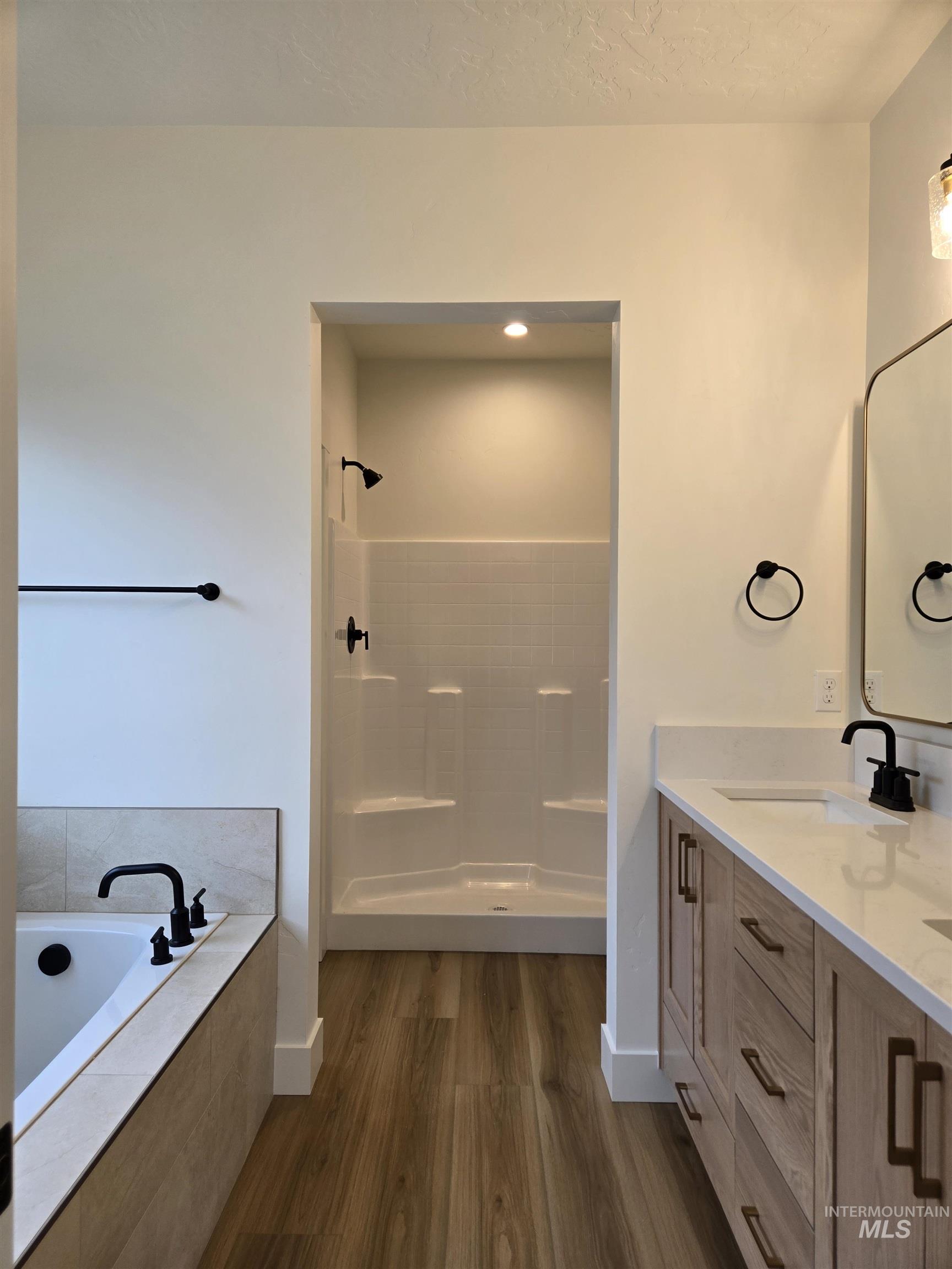 Bathroom with double vanity, walk in shower, a garden tub, and dark wood-style flooring