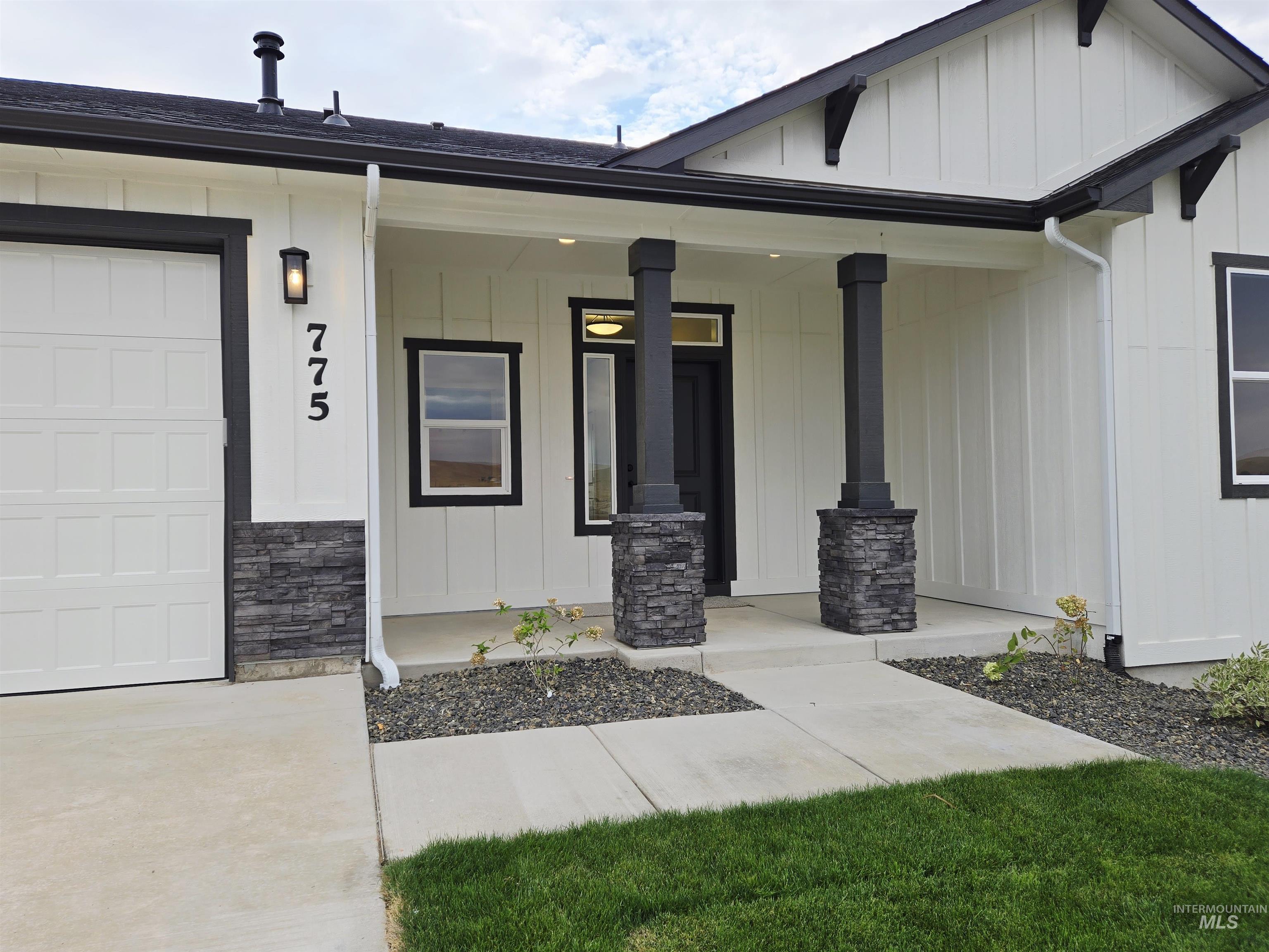 Entrance to property with a porch, board and batten siding, stone siding, and an attached garage