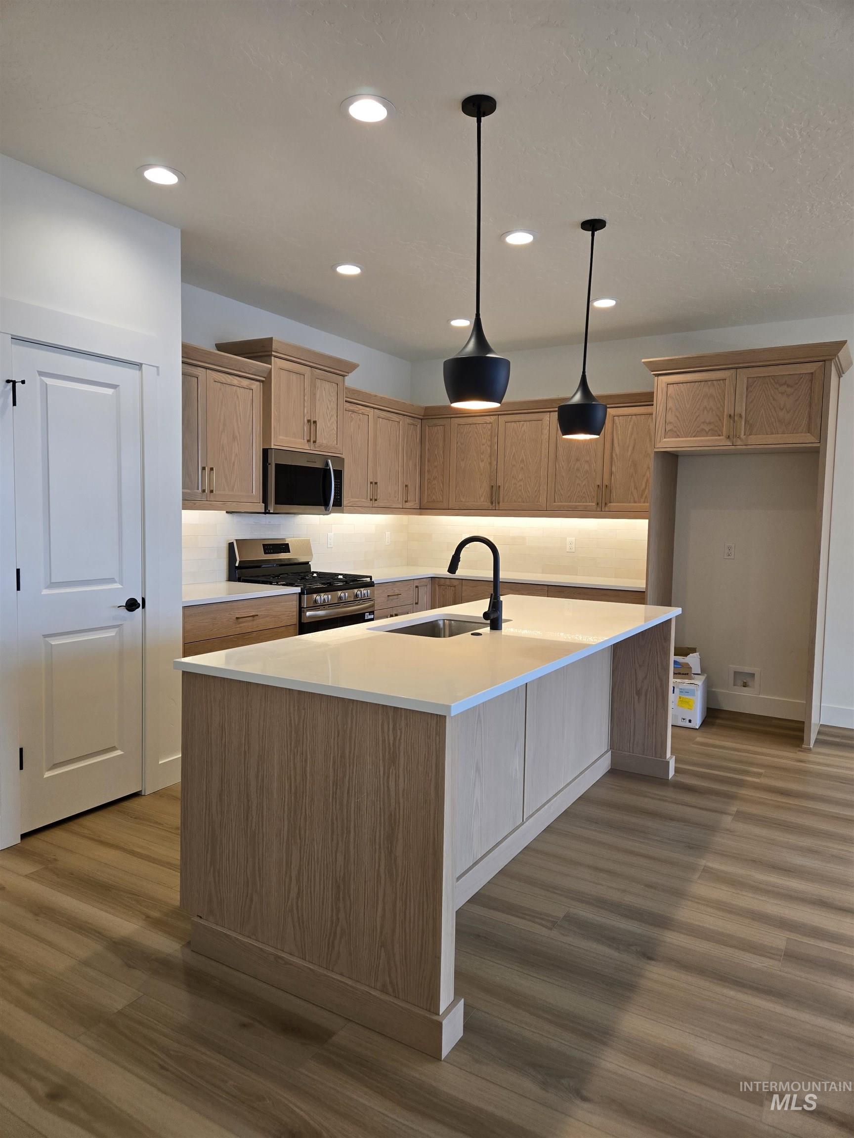 Kitchen with appliances with stainless steel finishes, recessed lighting, decorative light fixtures, backsplash, and dark wood-type flooring