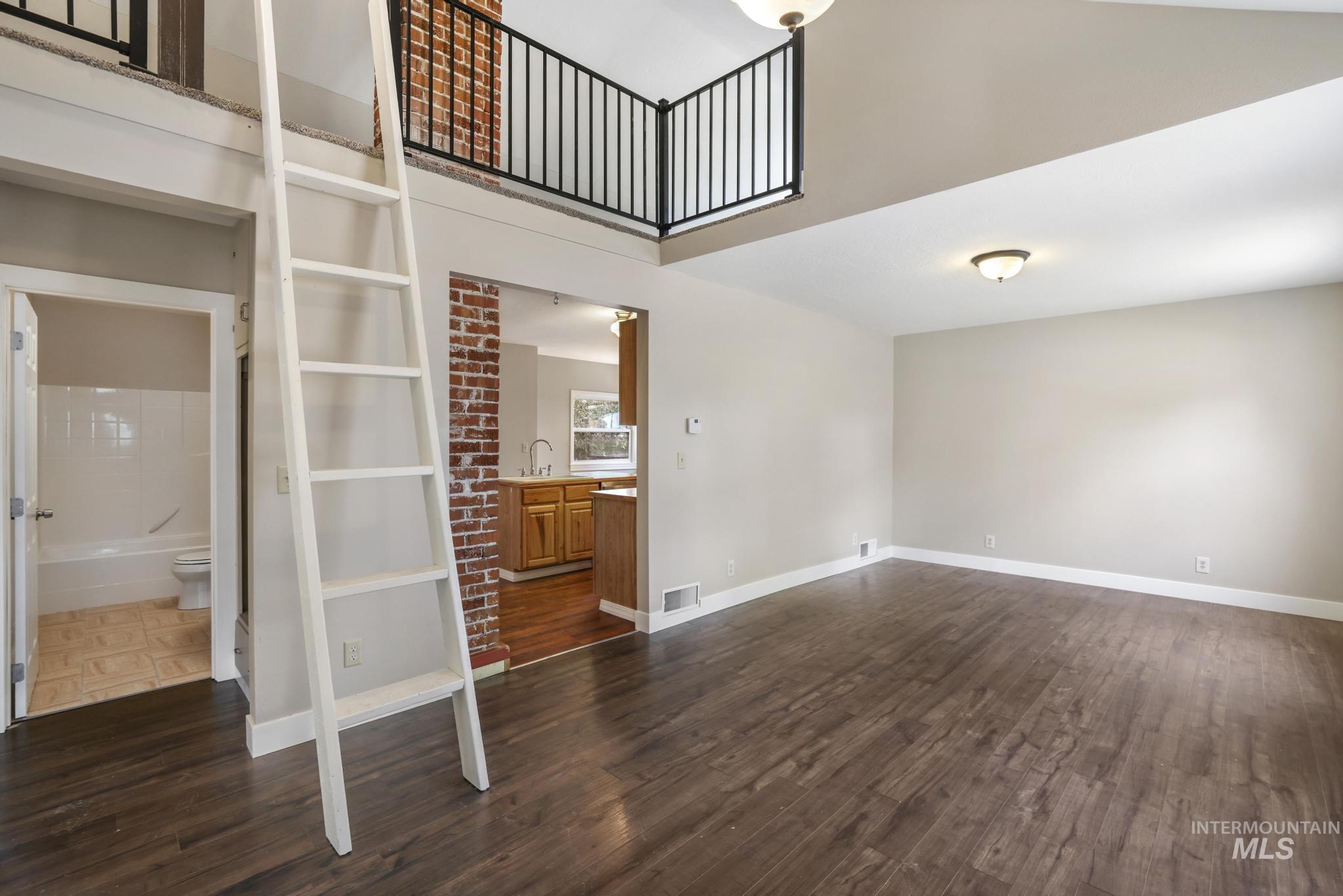 Unfurnished living room with dark wood-style floors and a towering ceiling