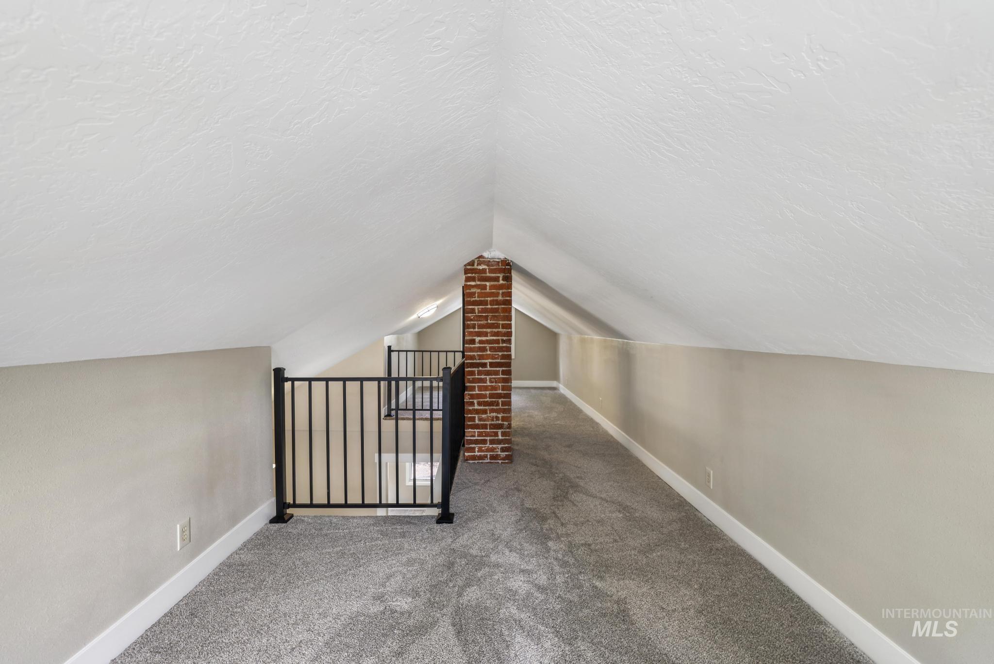 Additional living space featuring carpet flooring, lofted ceiling, and a textured ceiling