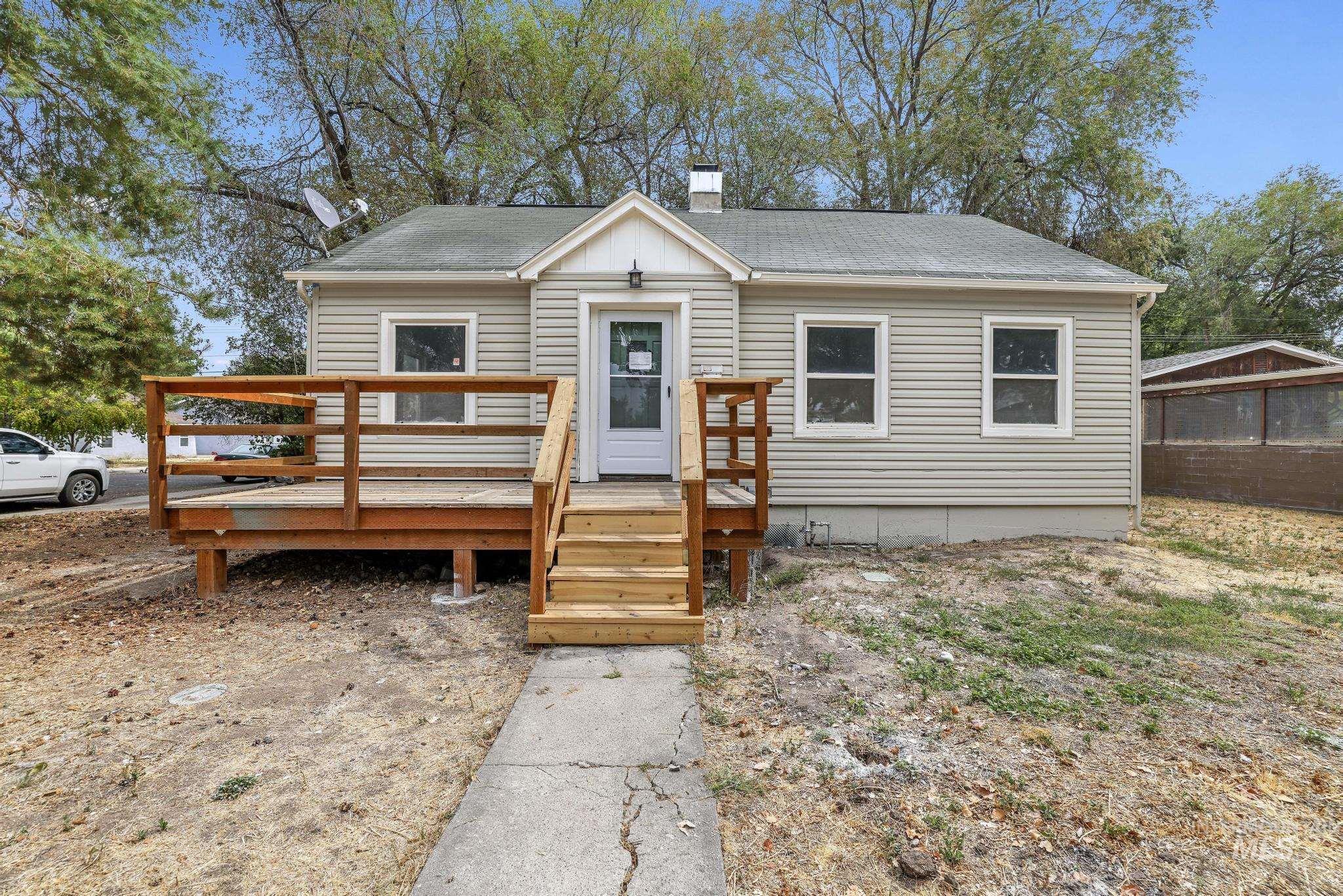 Bungalow-style home with roof with shingles, a chimney, and a wooden deck
