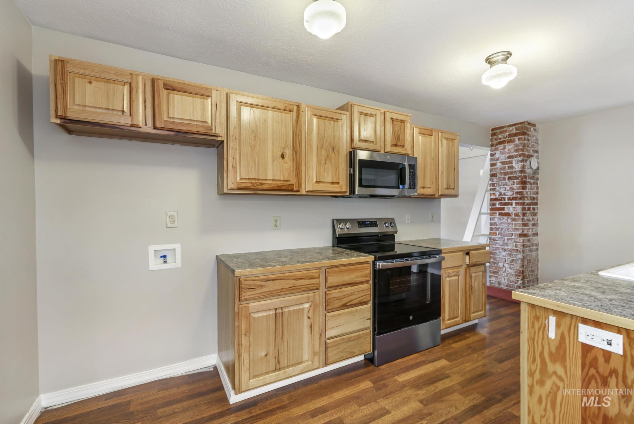 Kitchen featuring stainless steel appliances, dark wood finished floors, and light brown cabinets