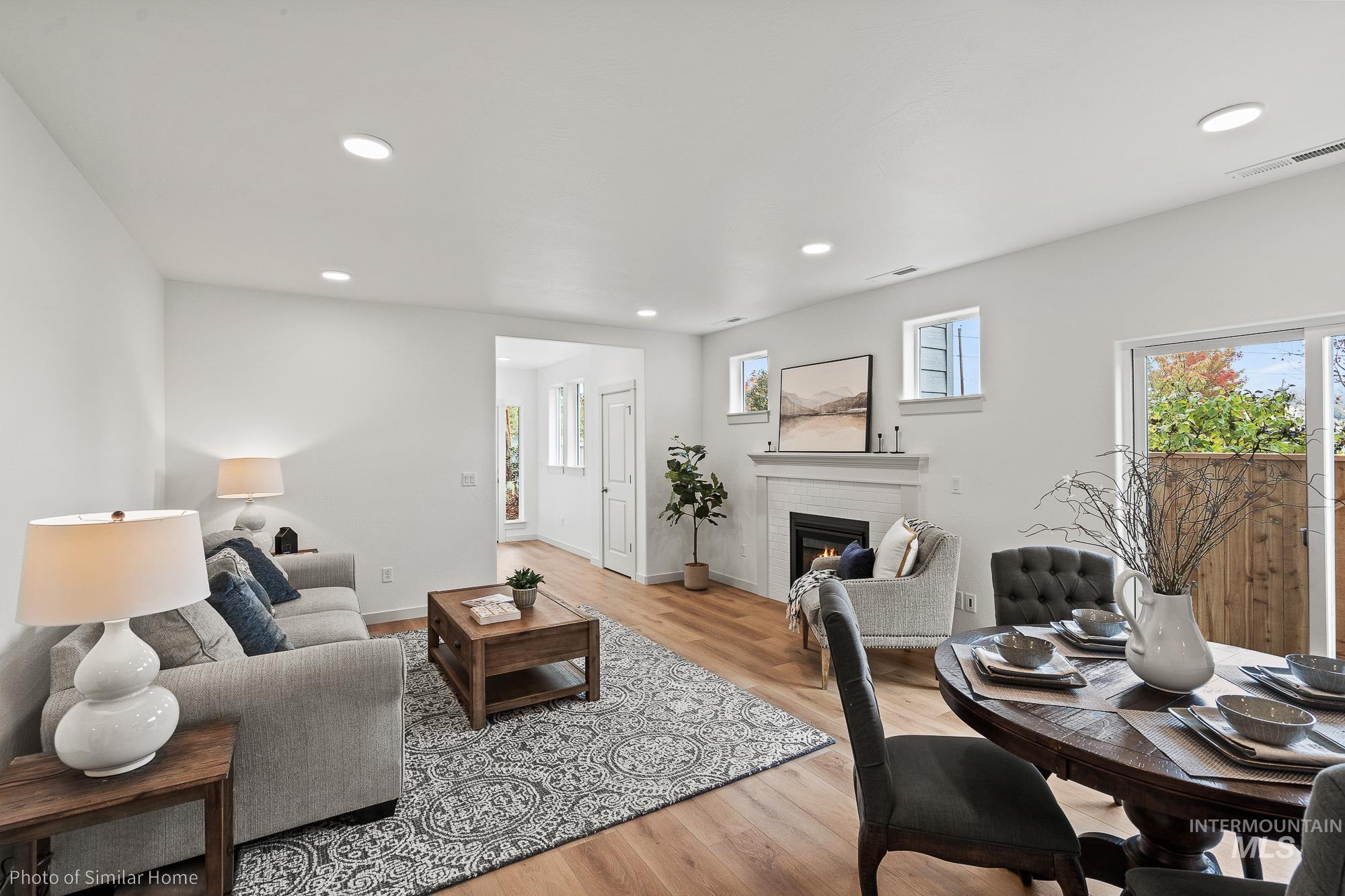 Living area featuring a brick fireplace, light wood-style flooring, recessed lighting, and healthy amount of natural light