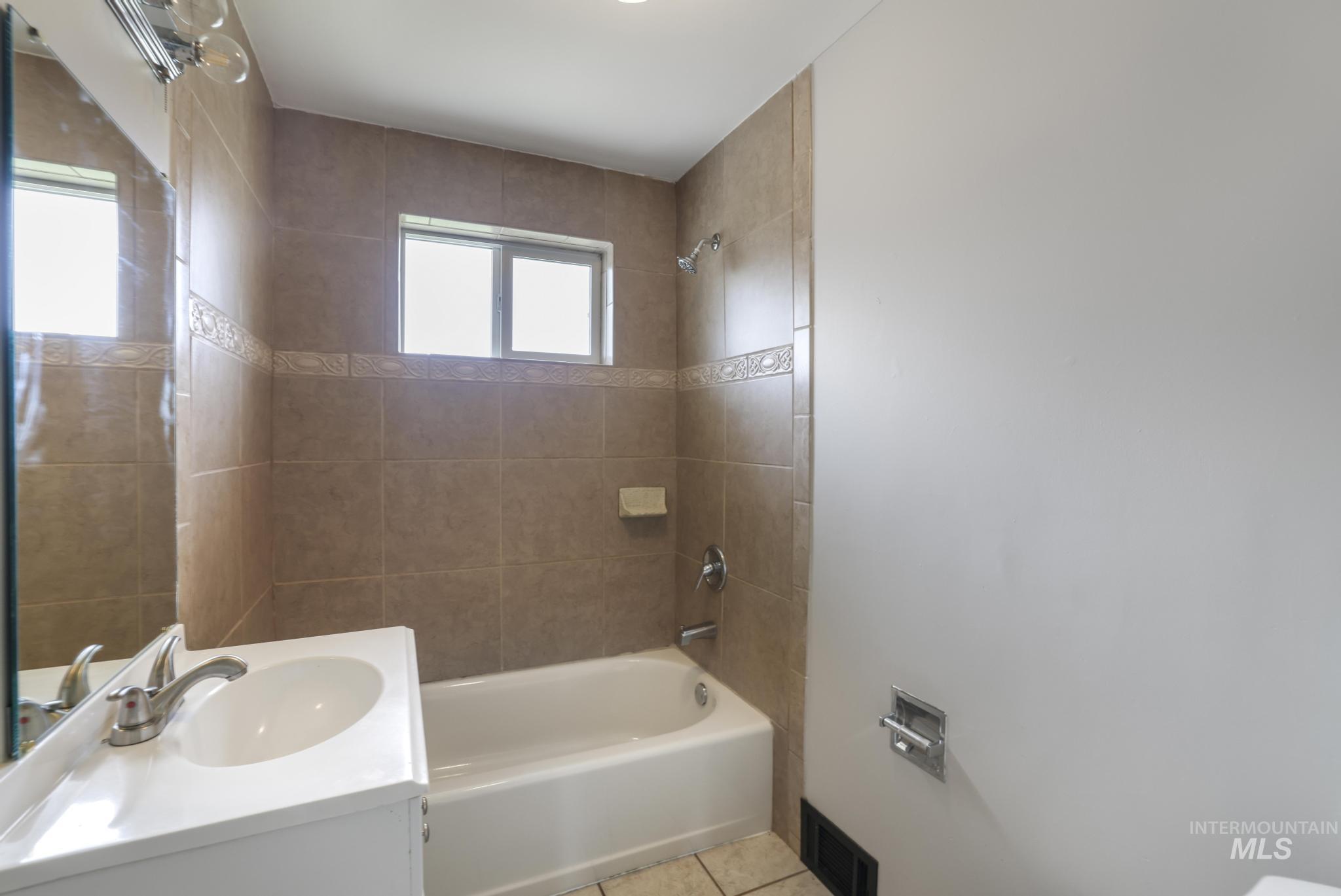 Full bathroom featuring washtub / shower combination, vanity, and light tile patterned floors