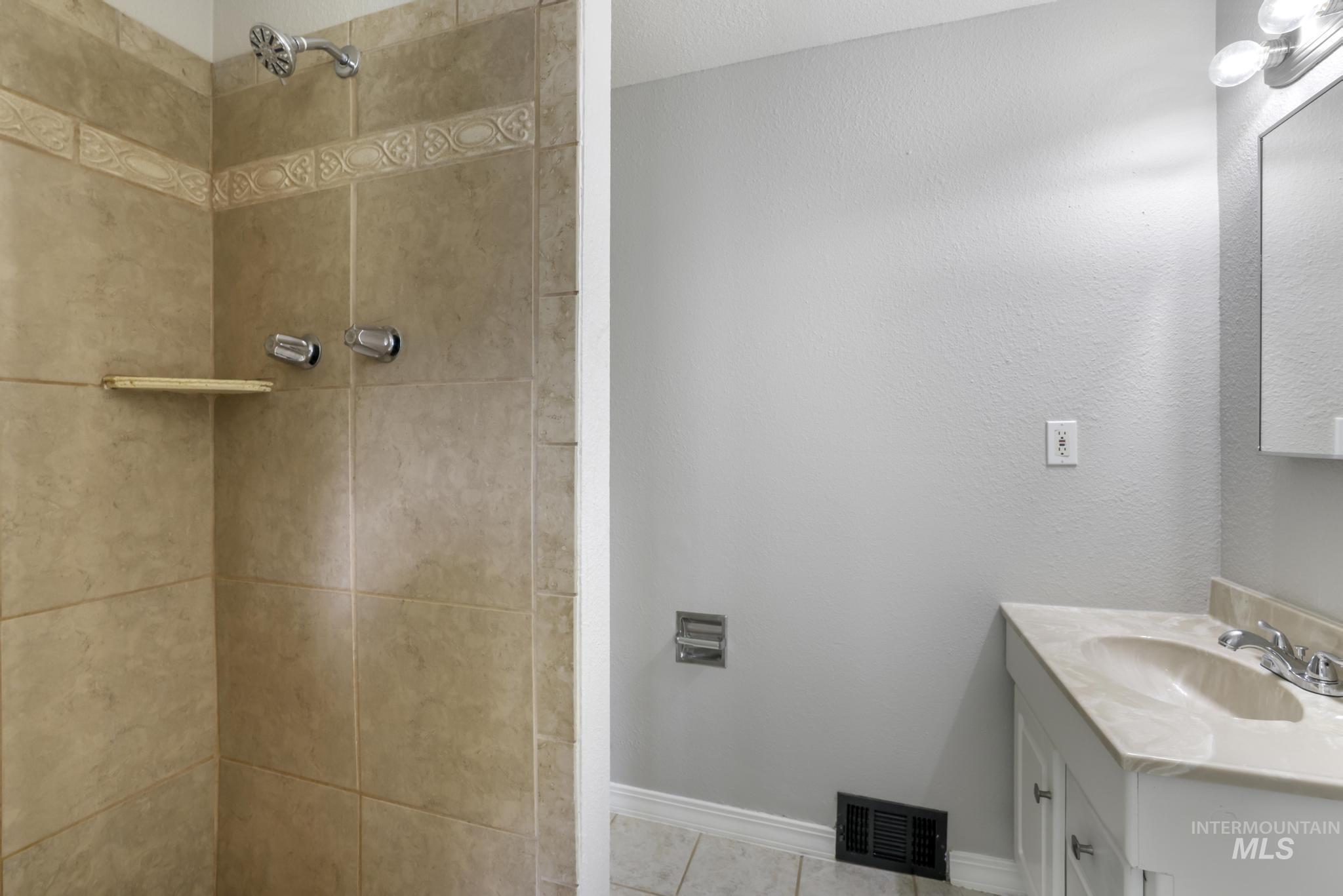 Bathroom with vanity, a shower stall, and tile patterned flooring