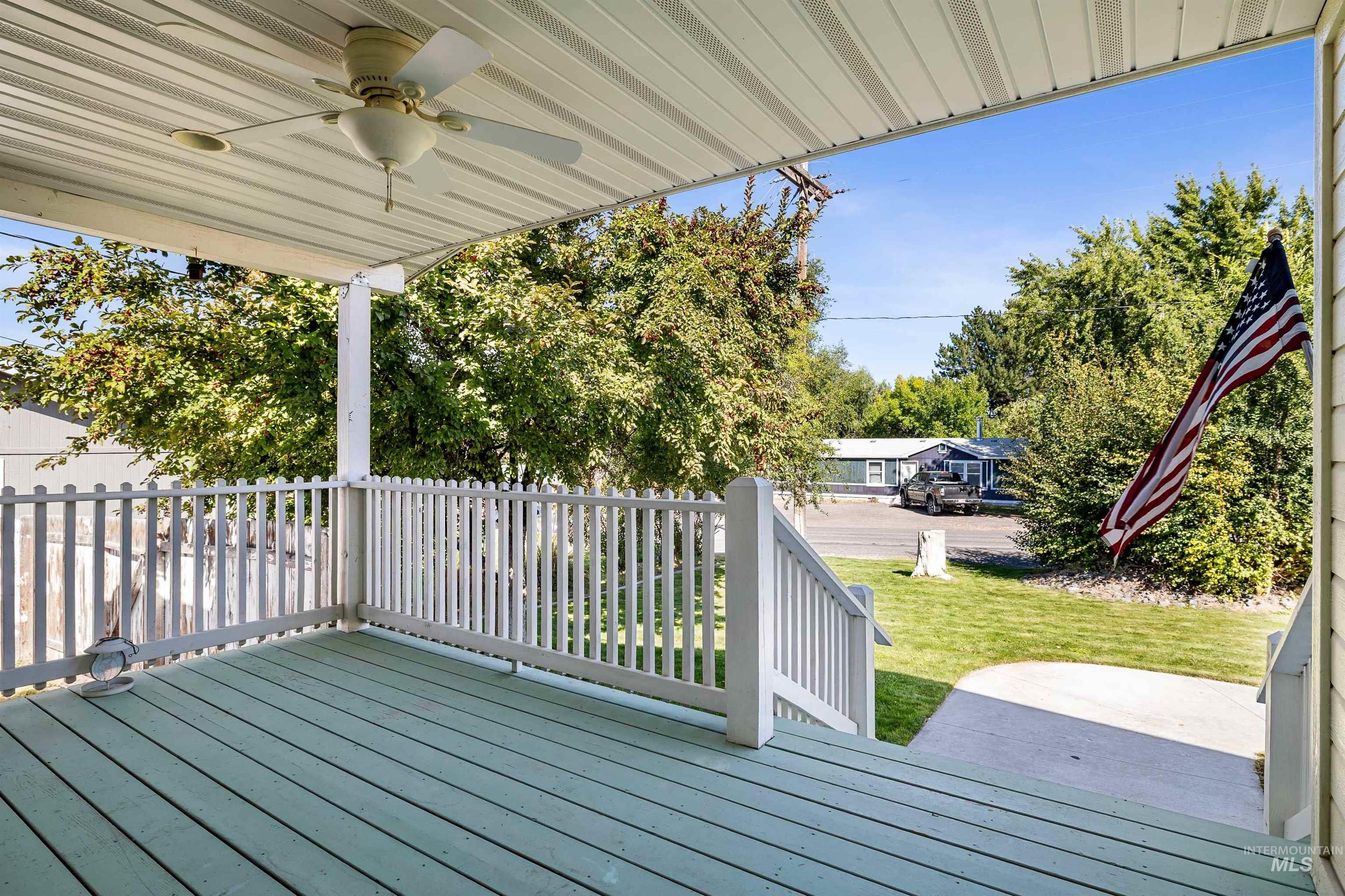 Wooden porch featuring ceiling fan and a yard