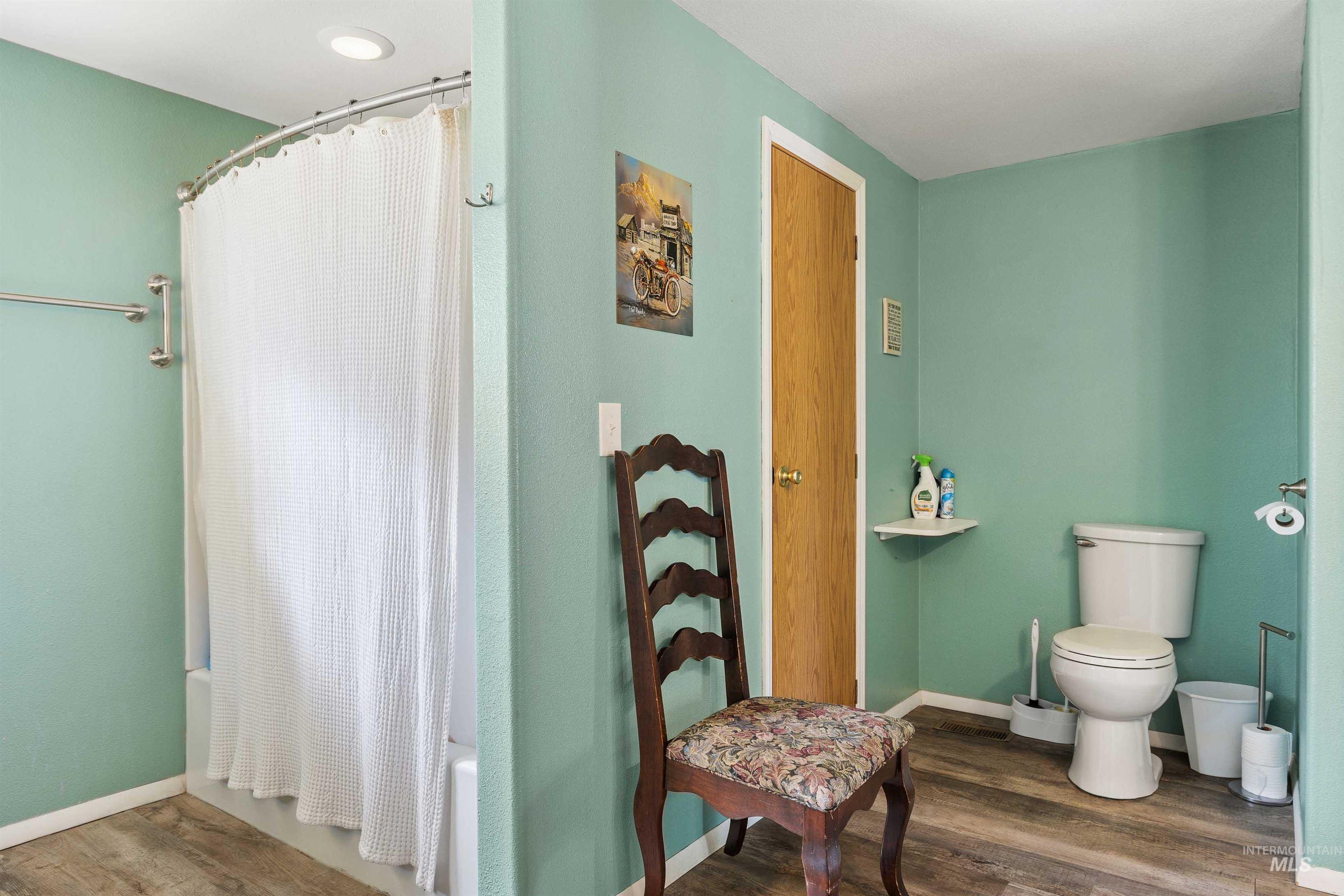Full bathroom featuring shower / tub combo with curtain and dark wood-style flooring