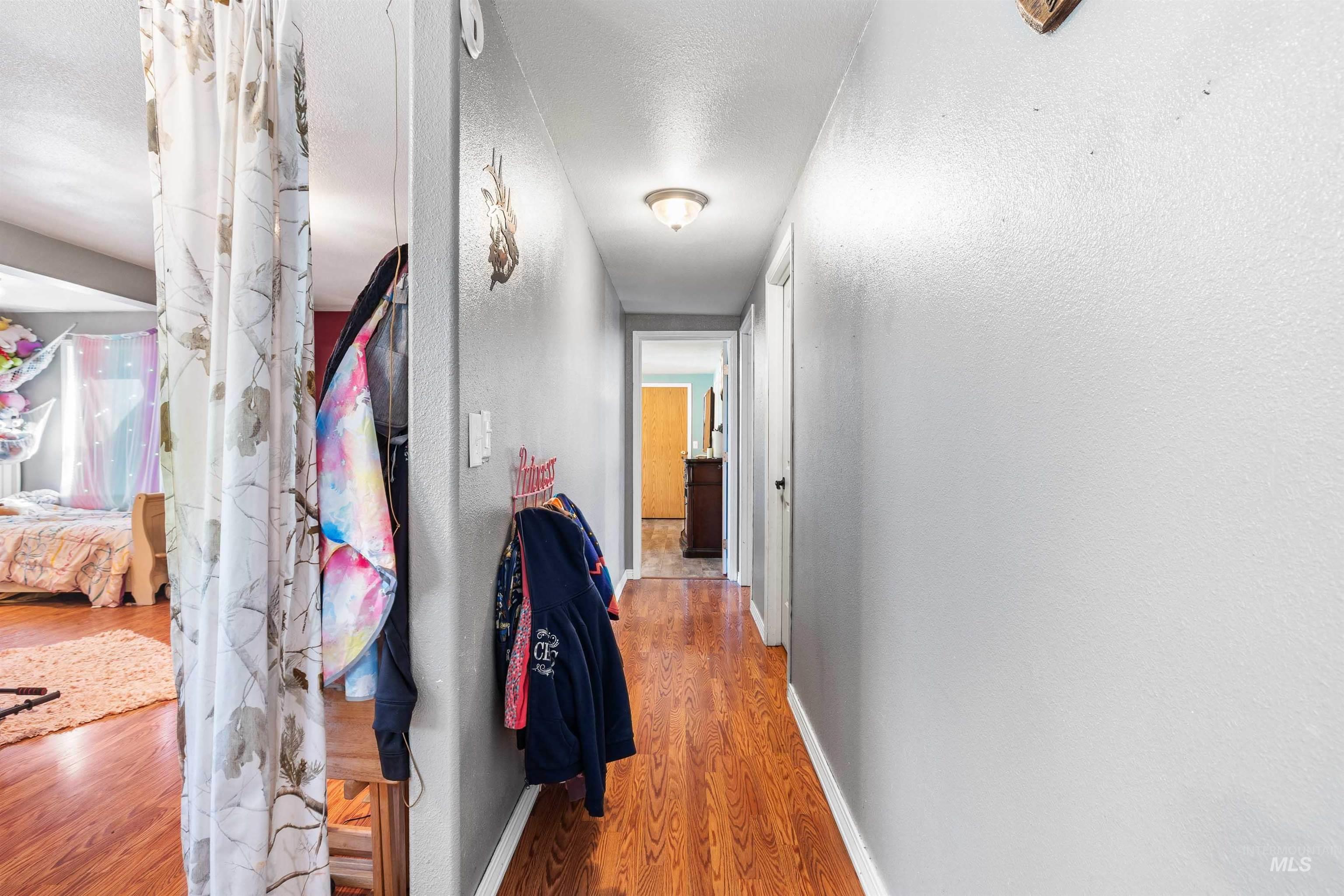 Hall with light wood-style floors, a textured ceiling, and a textured wall
