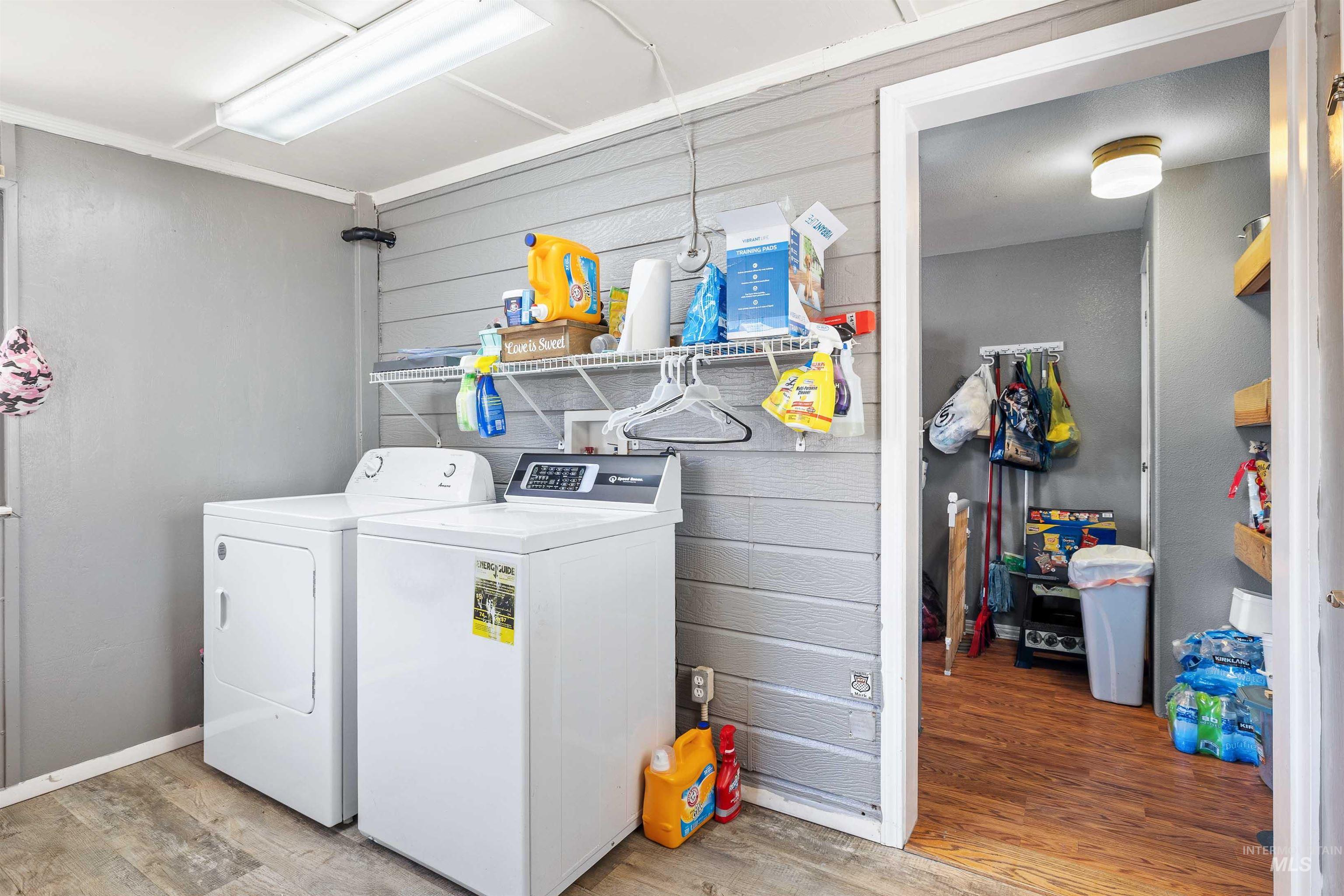 Laundry area featuring light wood finished floors, washing machine and dryer, and wooden walls