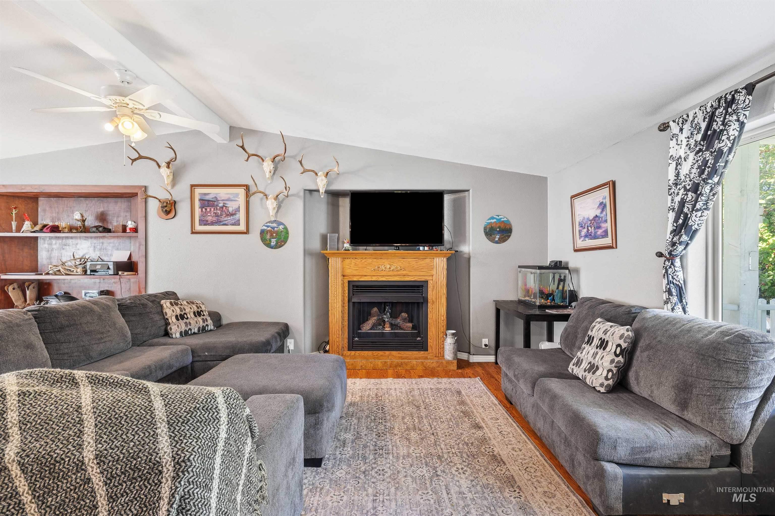 Living room with wood finished floors, a fireplace, and ceiling fan