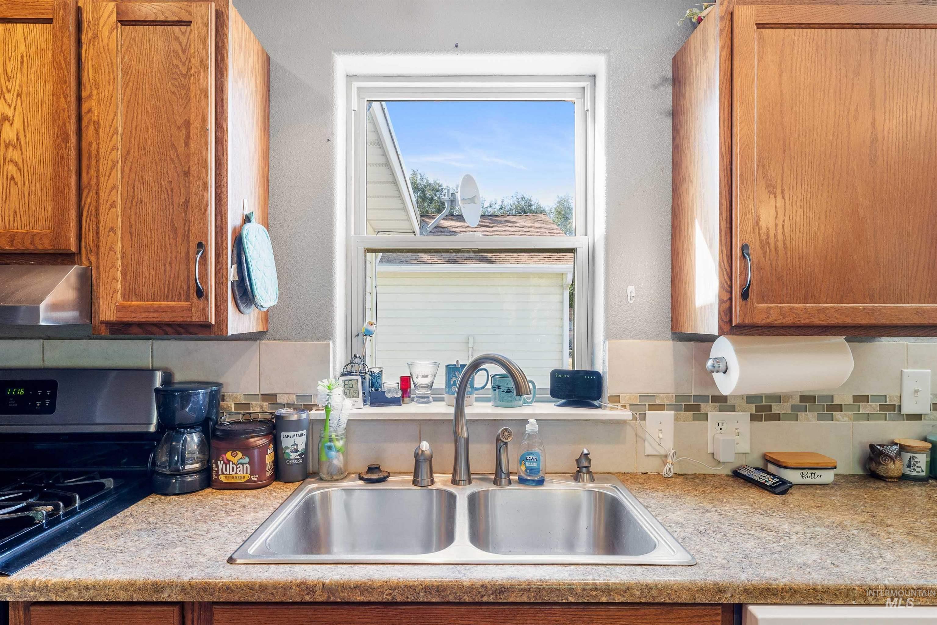 Kitchen featuring brown cabinetry, black range with gas stovetop, and light countertops
