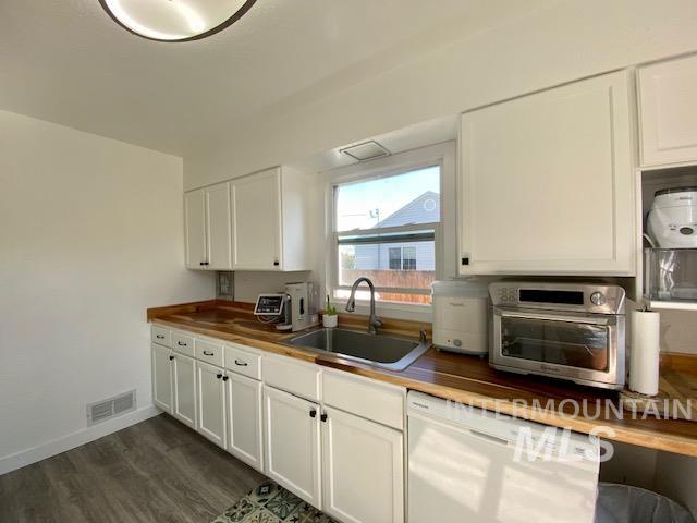 Kitchen featuring butcher block countertops, dishwasher, white cabinets, and dark wood-style flooring