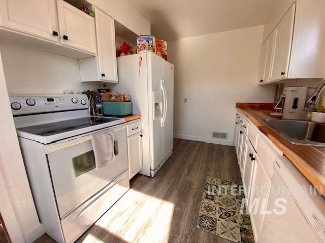 Kitchen featuring white appliances, white cabinets, and dark wood-type flooring