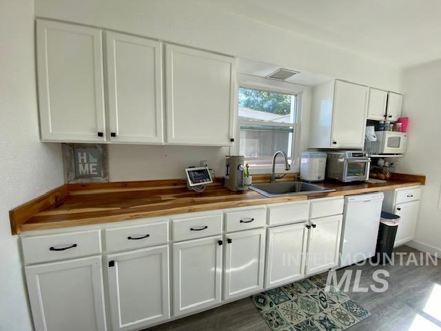 Kitchen featuring white cabinets, wood counters, white appliances, and dark wood-type flooring