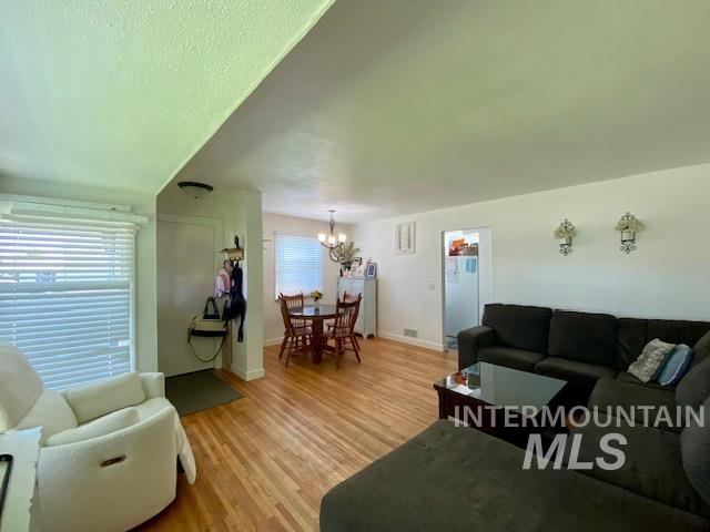 Living room featuring wood finished floors, healthy amount of natural light, and a chandelier