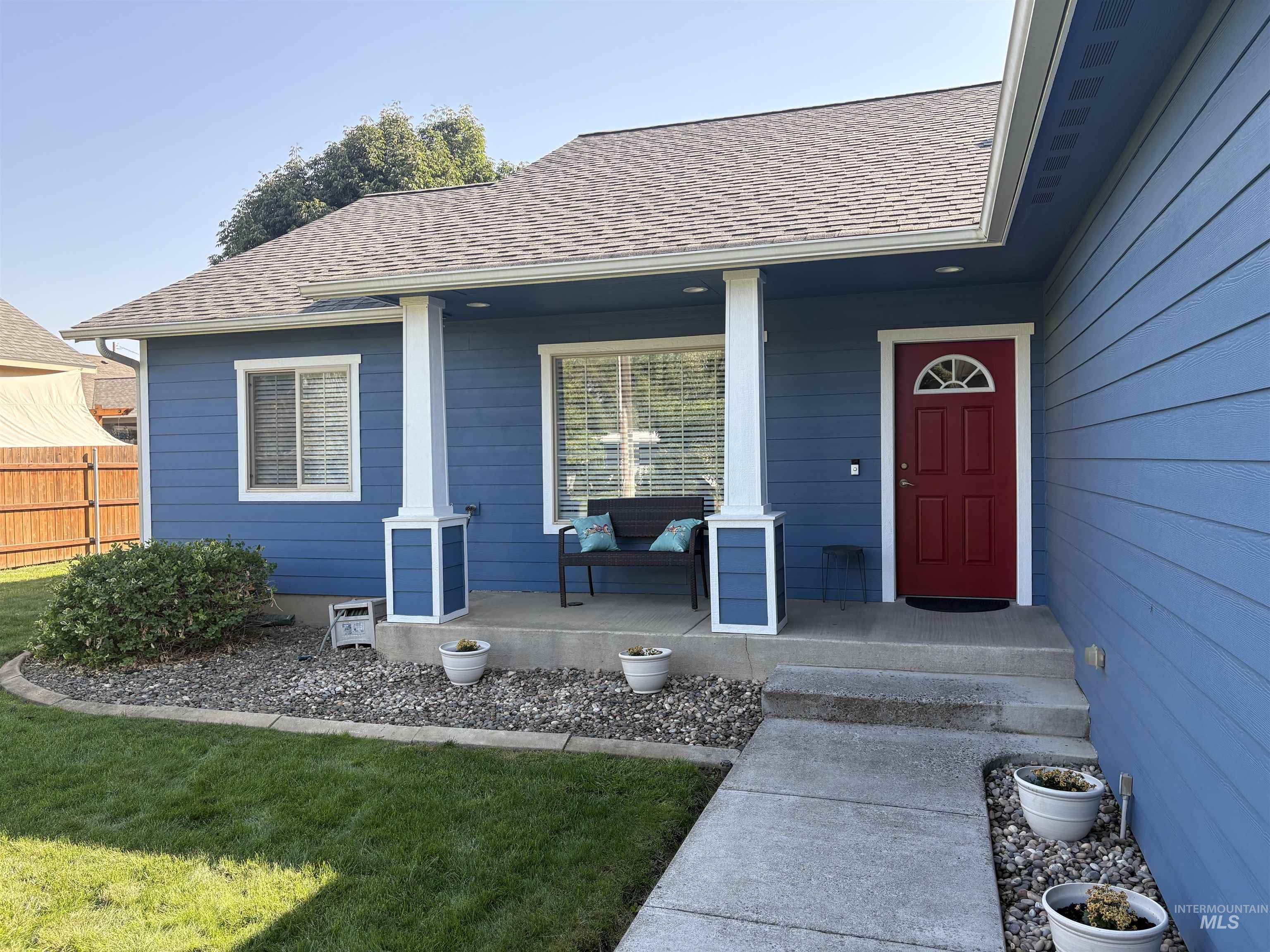 View of exterior entry with roof with shingles and a porch