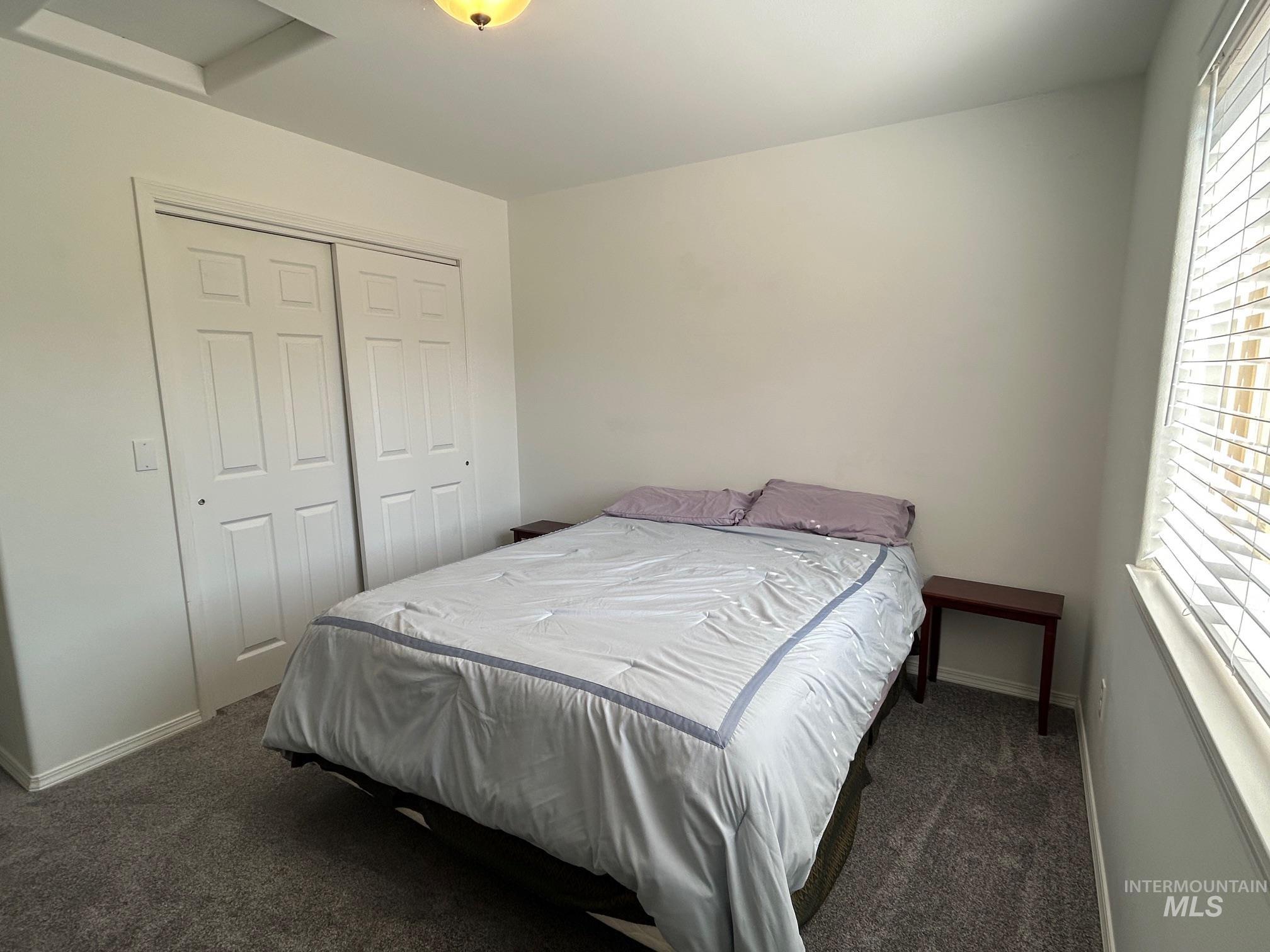 Bedroom with dark colored carpet and a closet