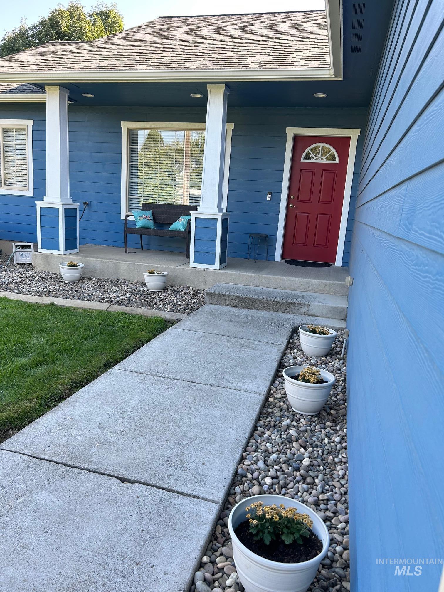 Property entrance featuring covered porch and a shingled roof