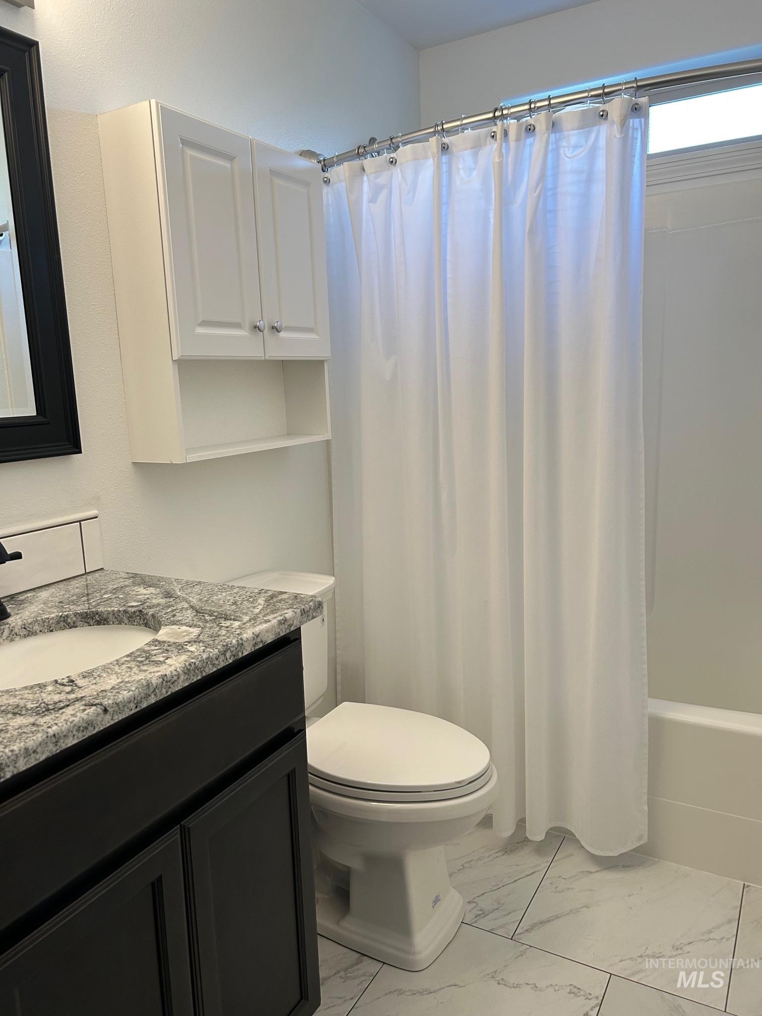 Full bath featuring vanity, light marble finish flooring, and shower / bathtub combination with curtain