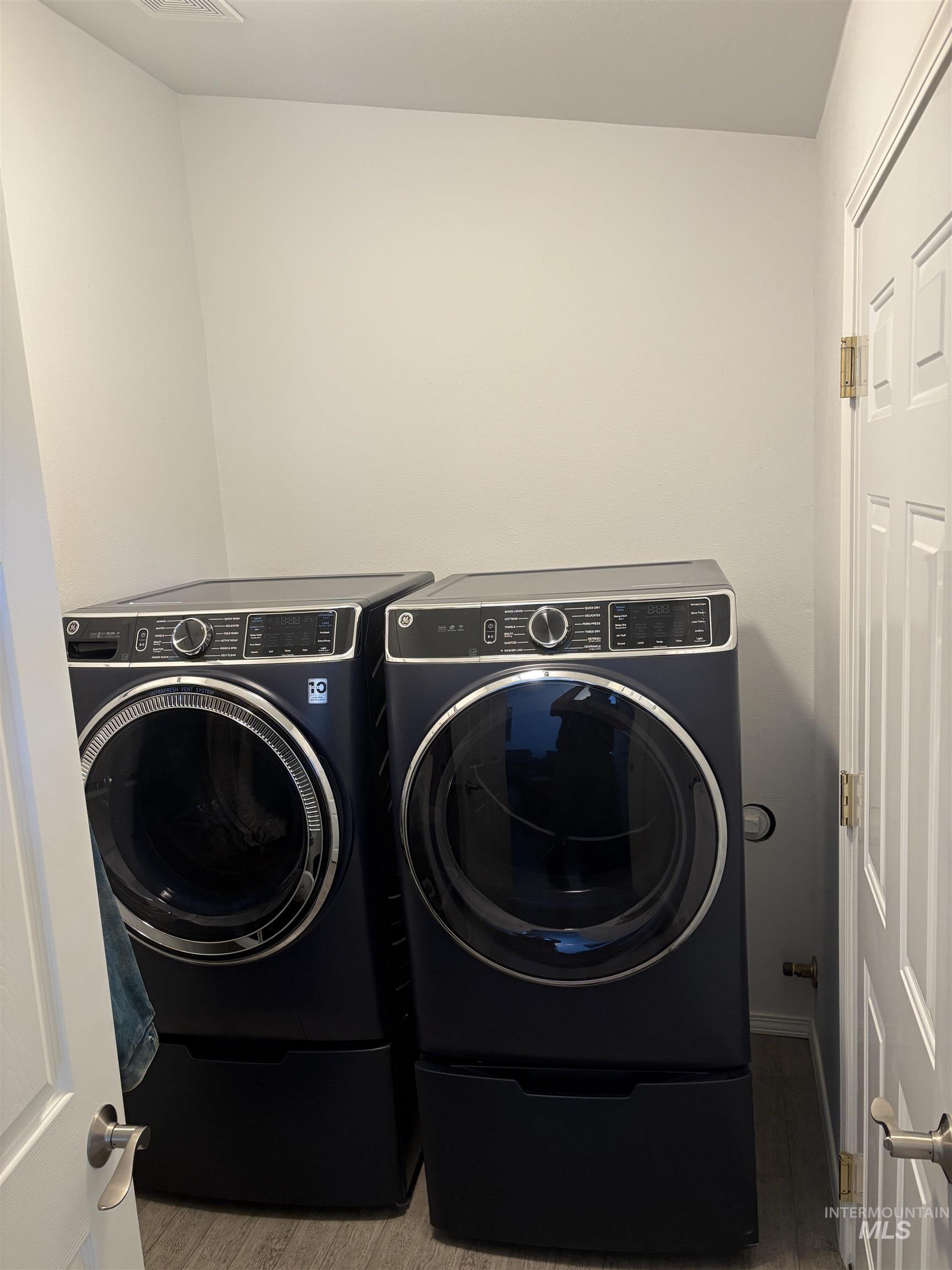 Laundry room with wood finished floors and washer and dryer