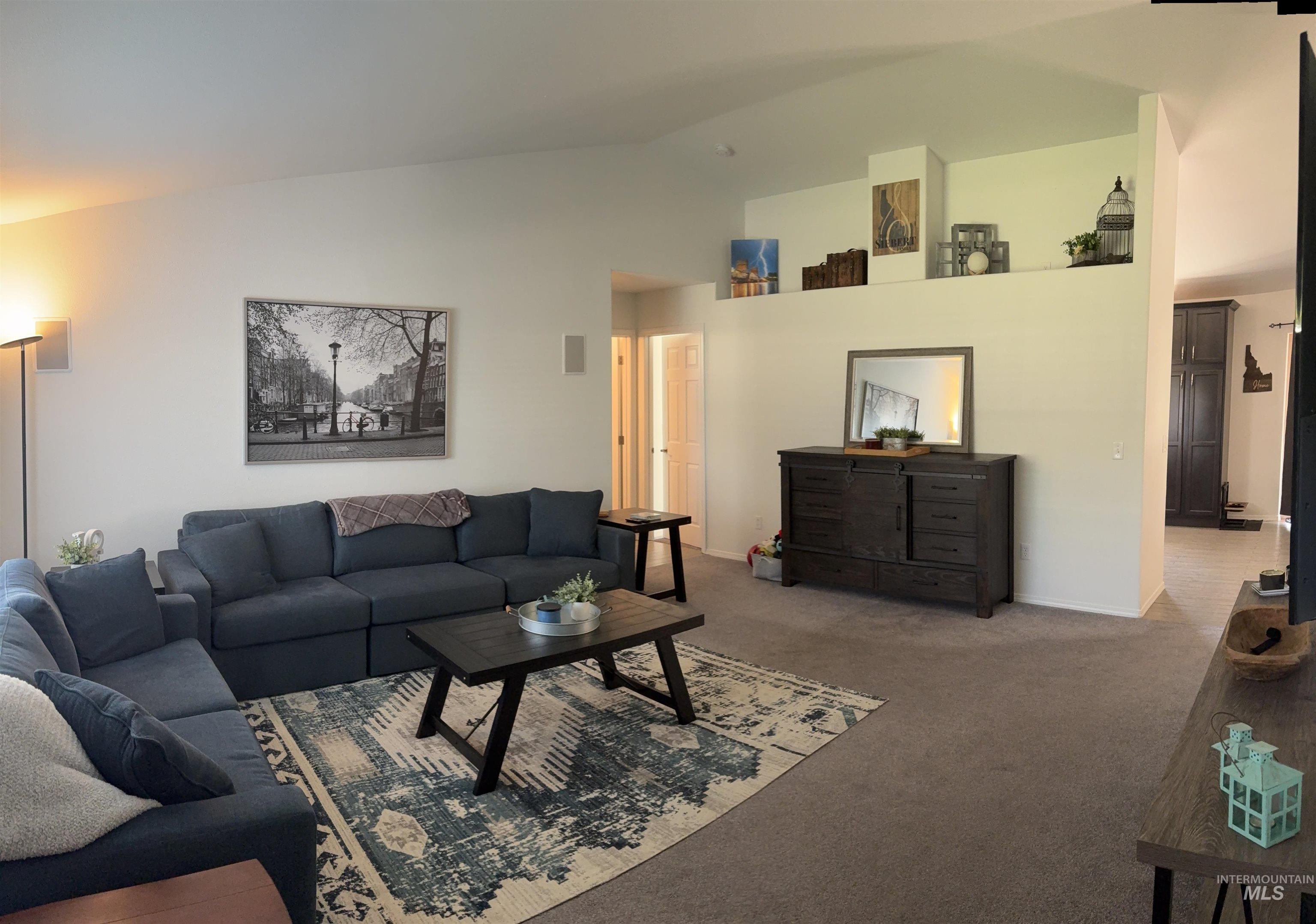 Carpeted living room featuring lofted ceiling