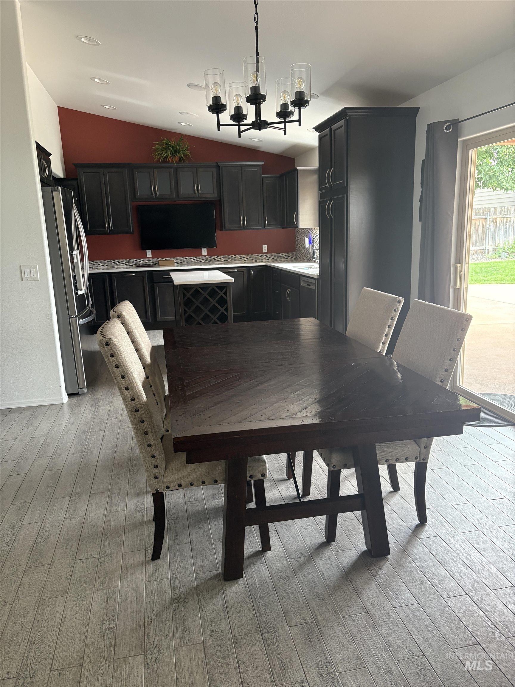 Dining space with vaulted ceiling, light wood-style flooring, and a chandelier