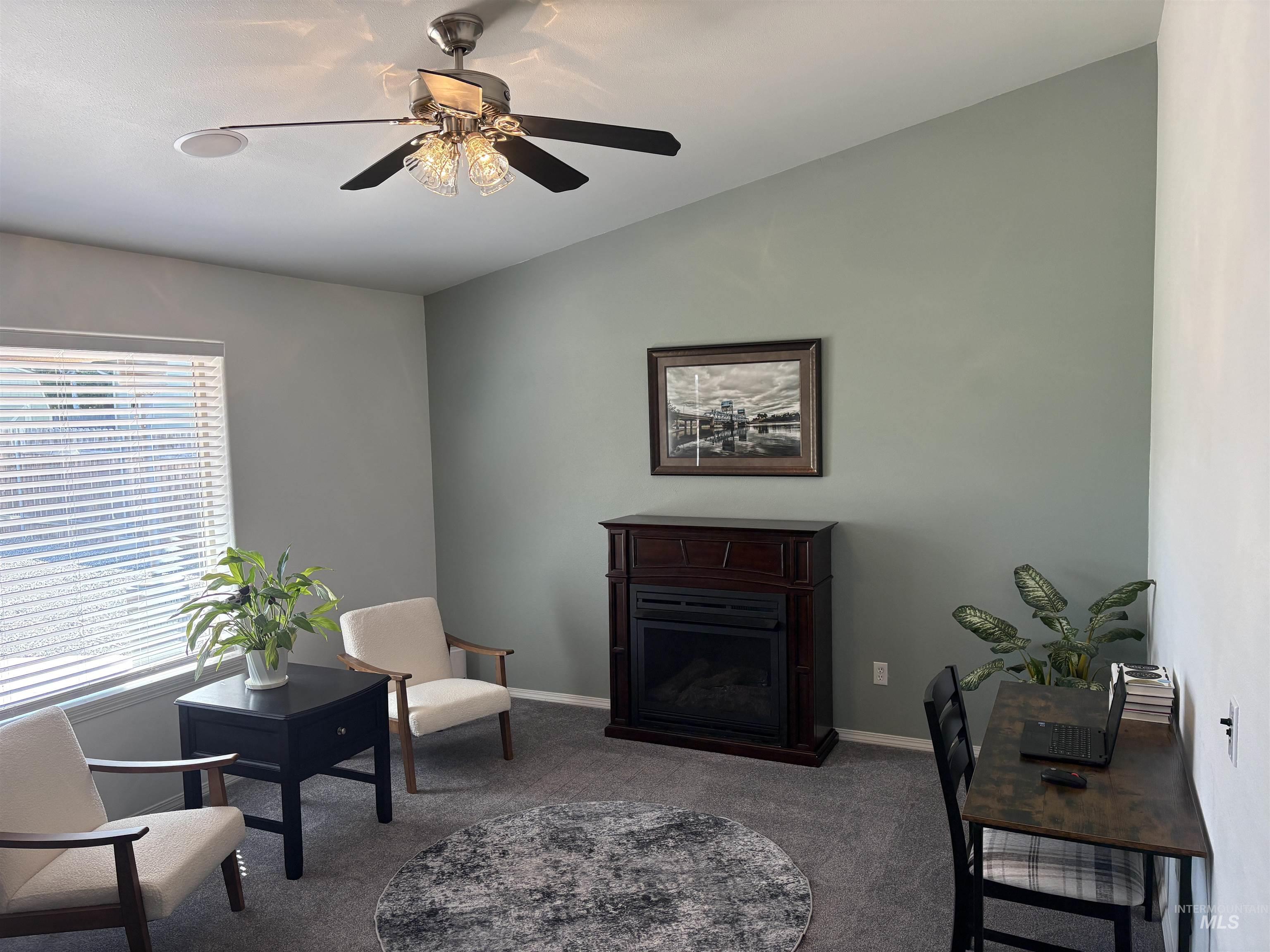 Living area with carpet floors, a fireplace, and a ceiling fan