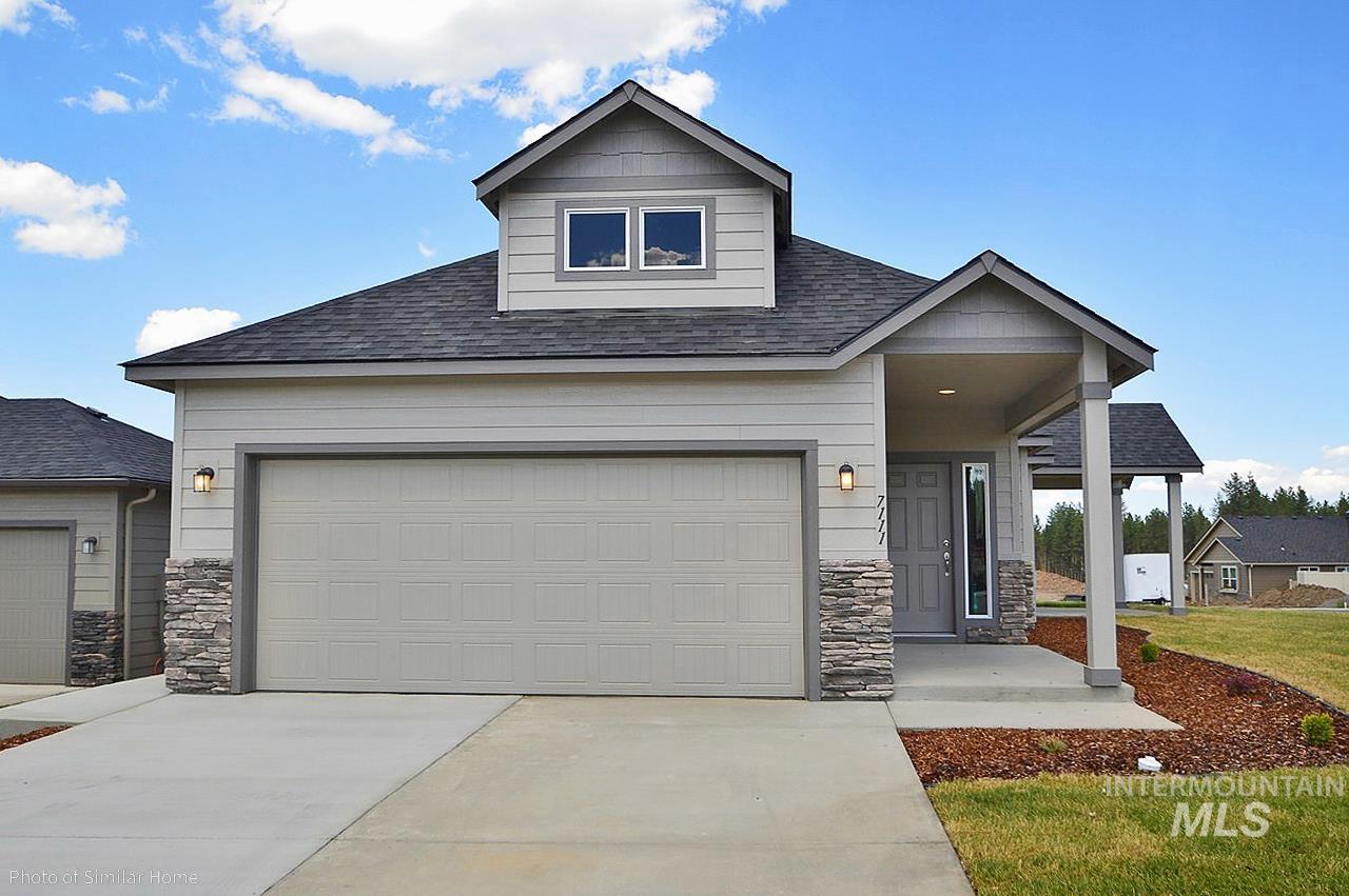 View of front of house with a shingled roof, stone siding, driveway, and covered porch