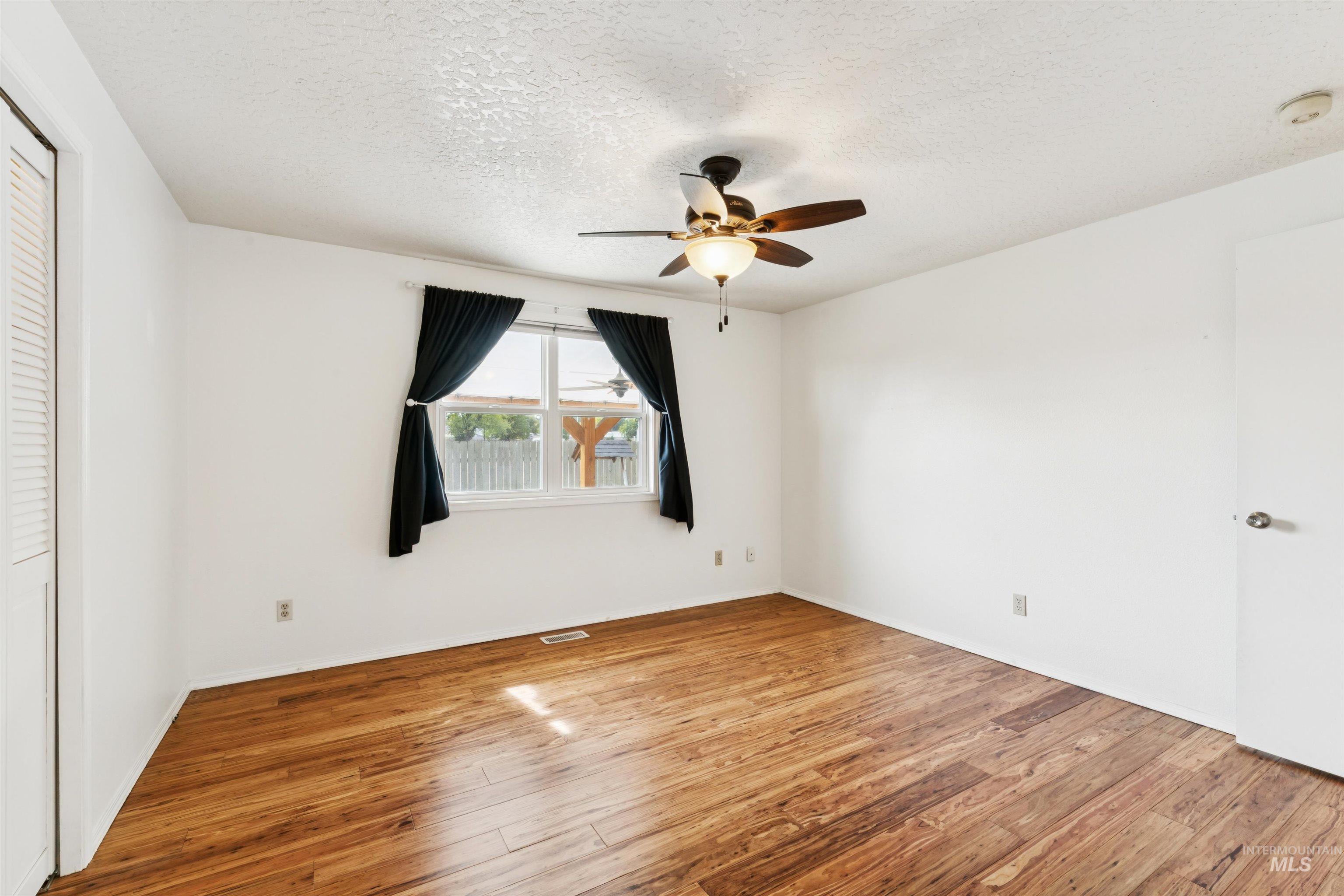 Unfurnished bedroom featuring light wood-type flooring, a textured ceiling, a ceiling fan, and a closet