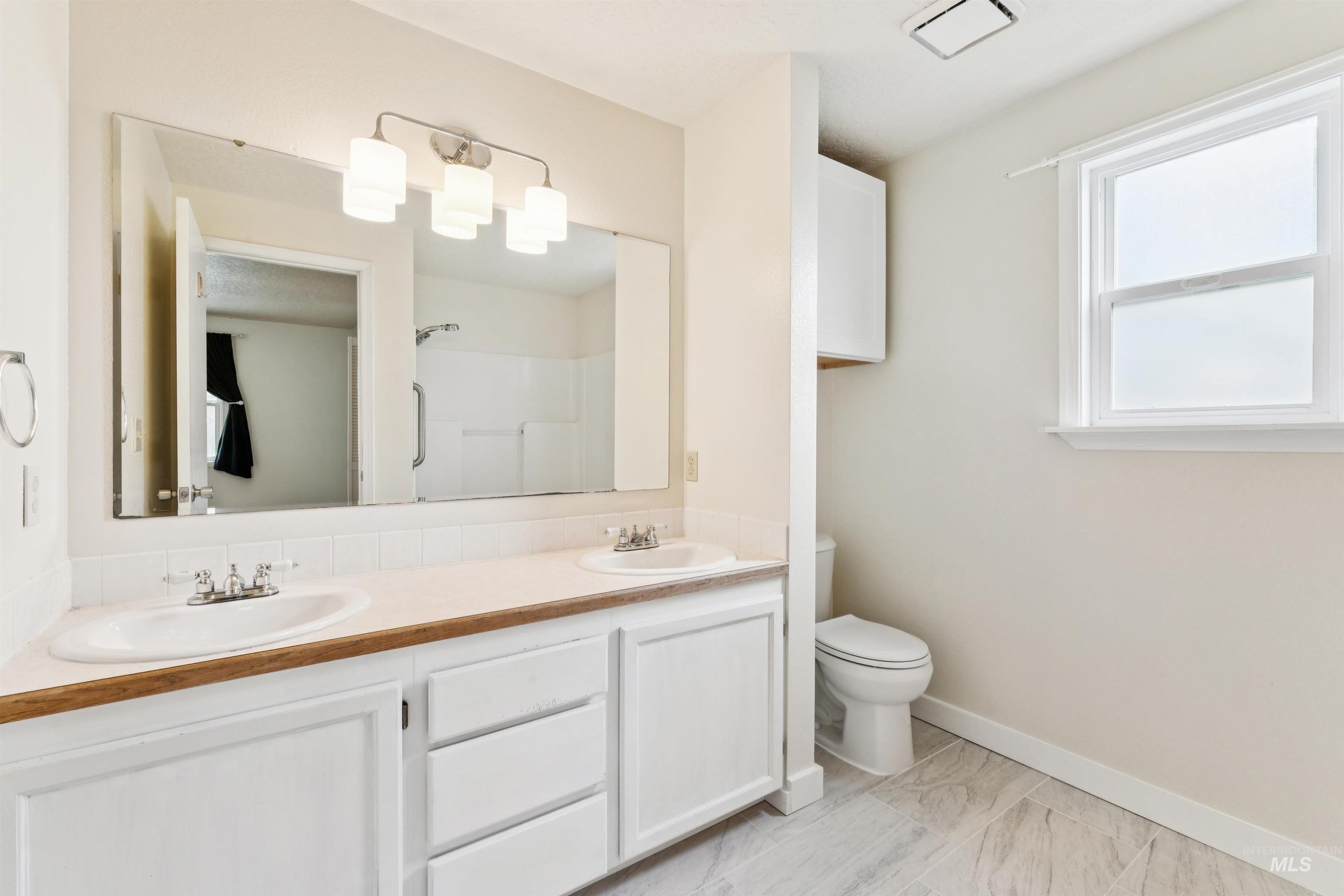 Full bath featuring a shower and double vanity
