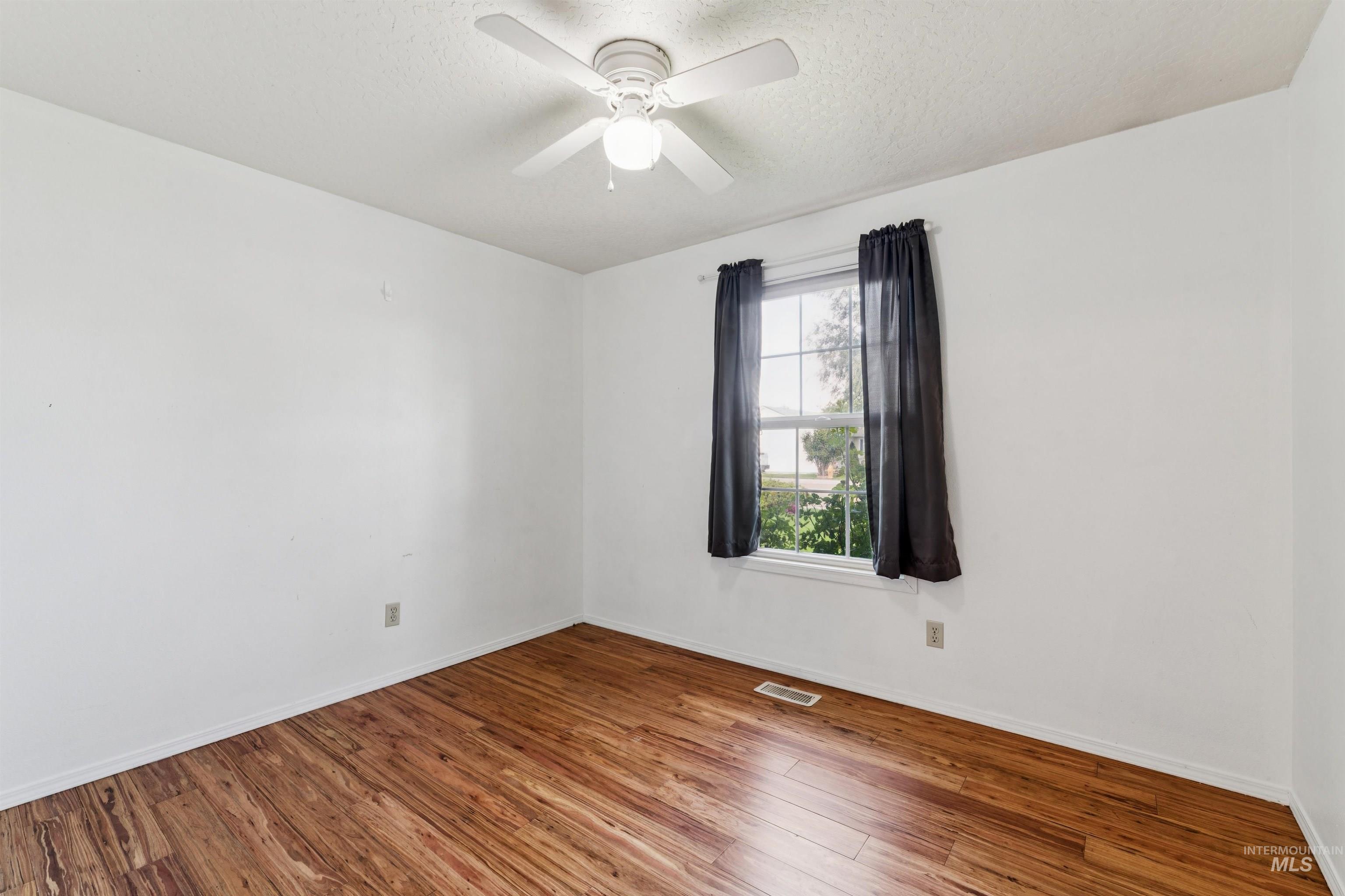 Spare room featuring wood finished floors, a textured ceiling, and a ceiling fan