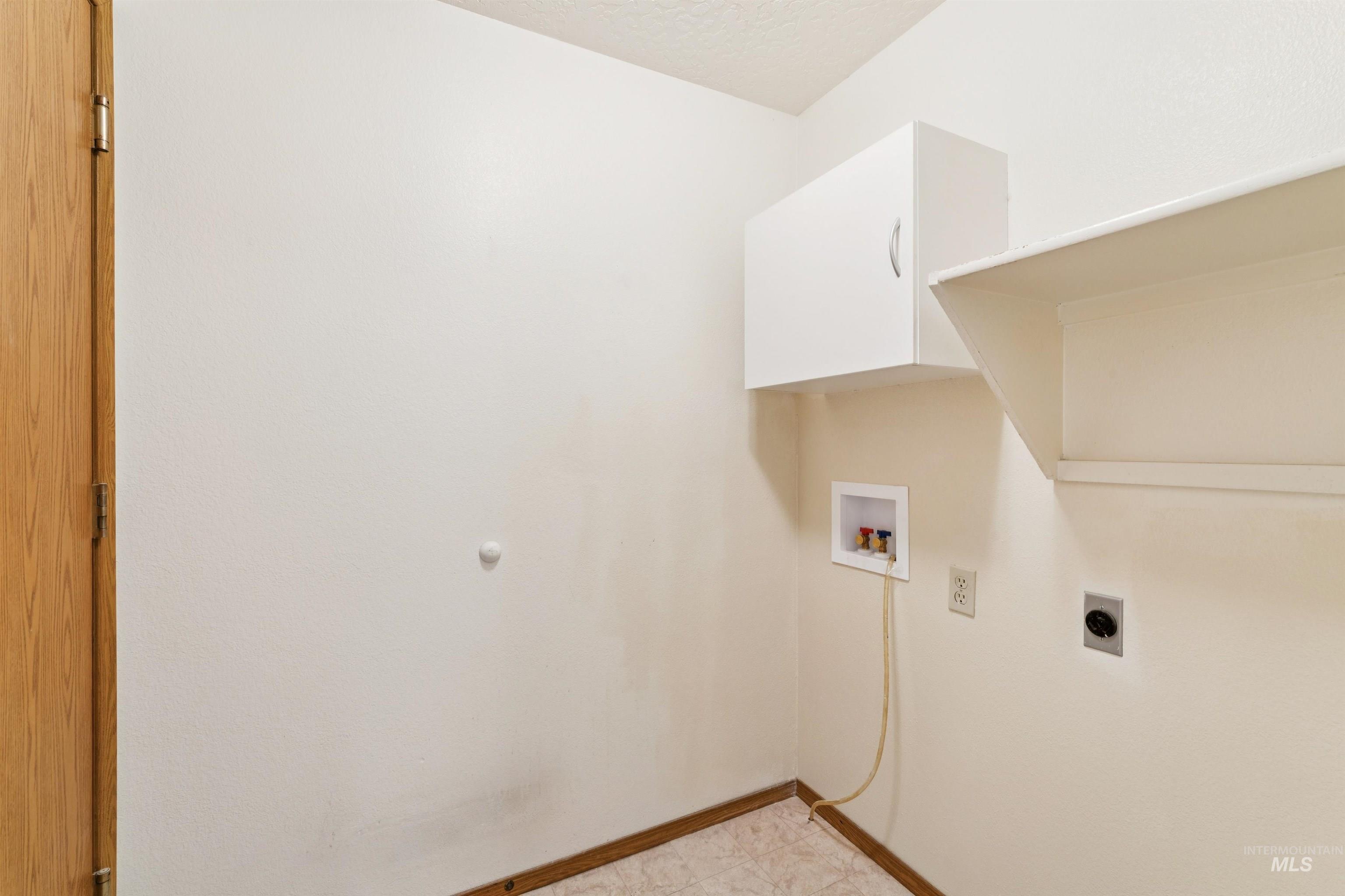 Washroom featuring hookup for a washing machine, a textured ceiling, cabinet space, and electric dryer hookup