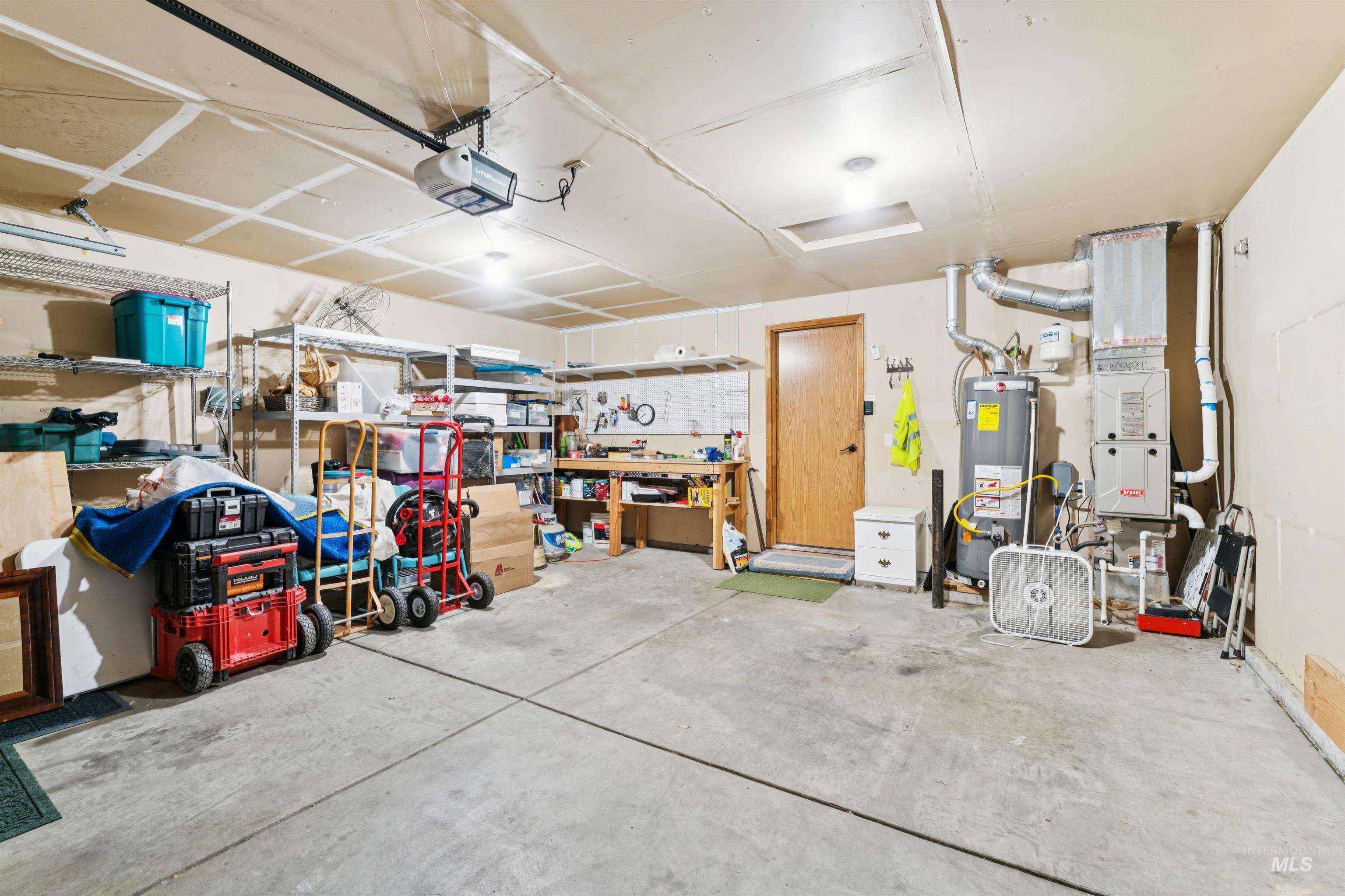 Garage with water heater, a garage door opener, and a workshop area