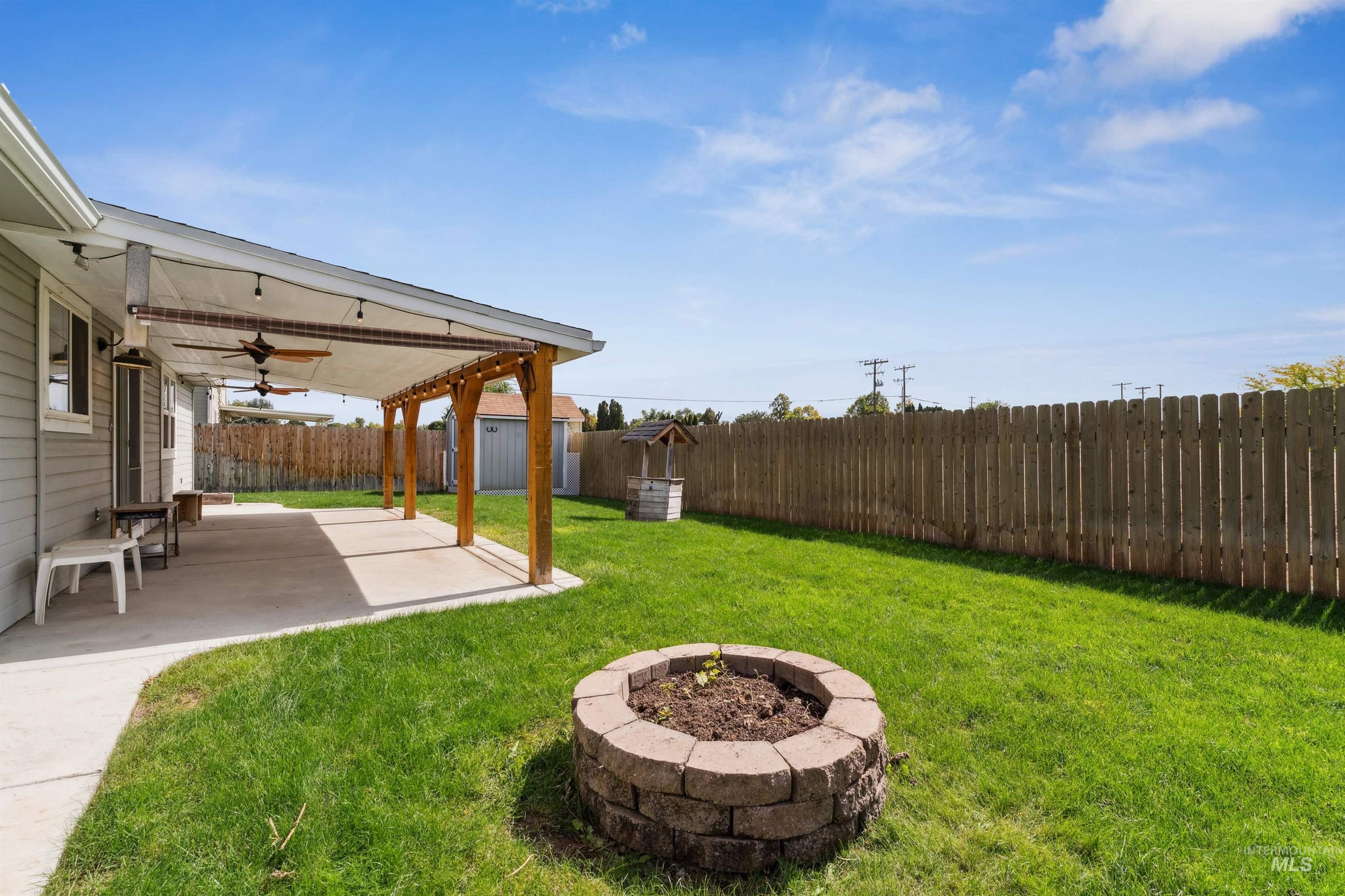 Fenced backyard with a patio, a ceiling fan, and an outdoor structure