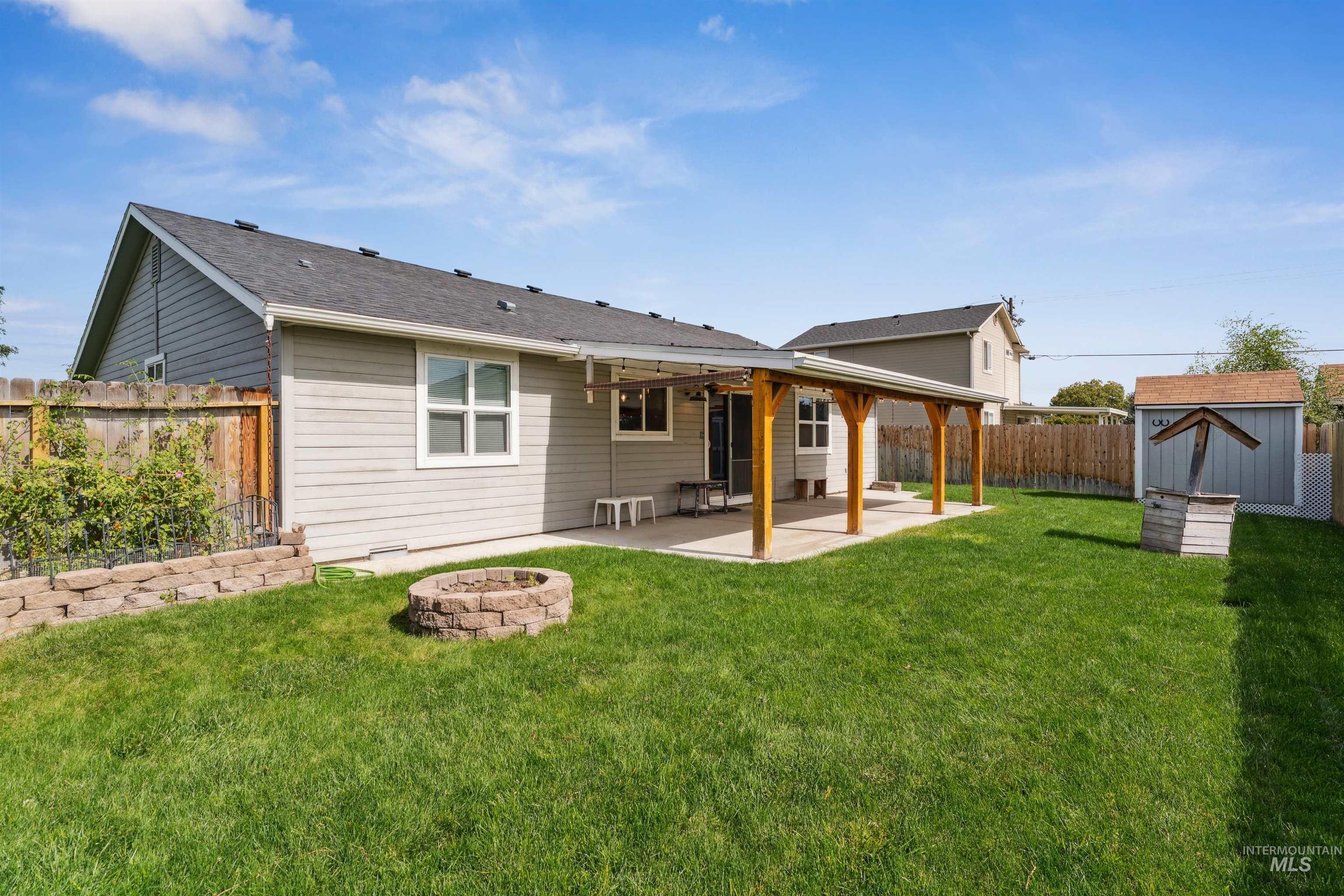Rear view of house featuring an outdoor fire pit, a patio area, a shed, and a fenced backyard
