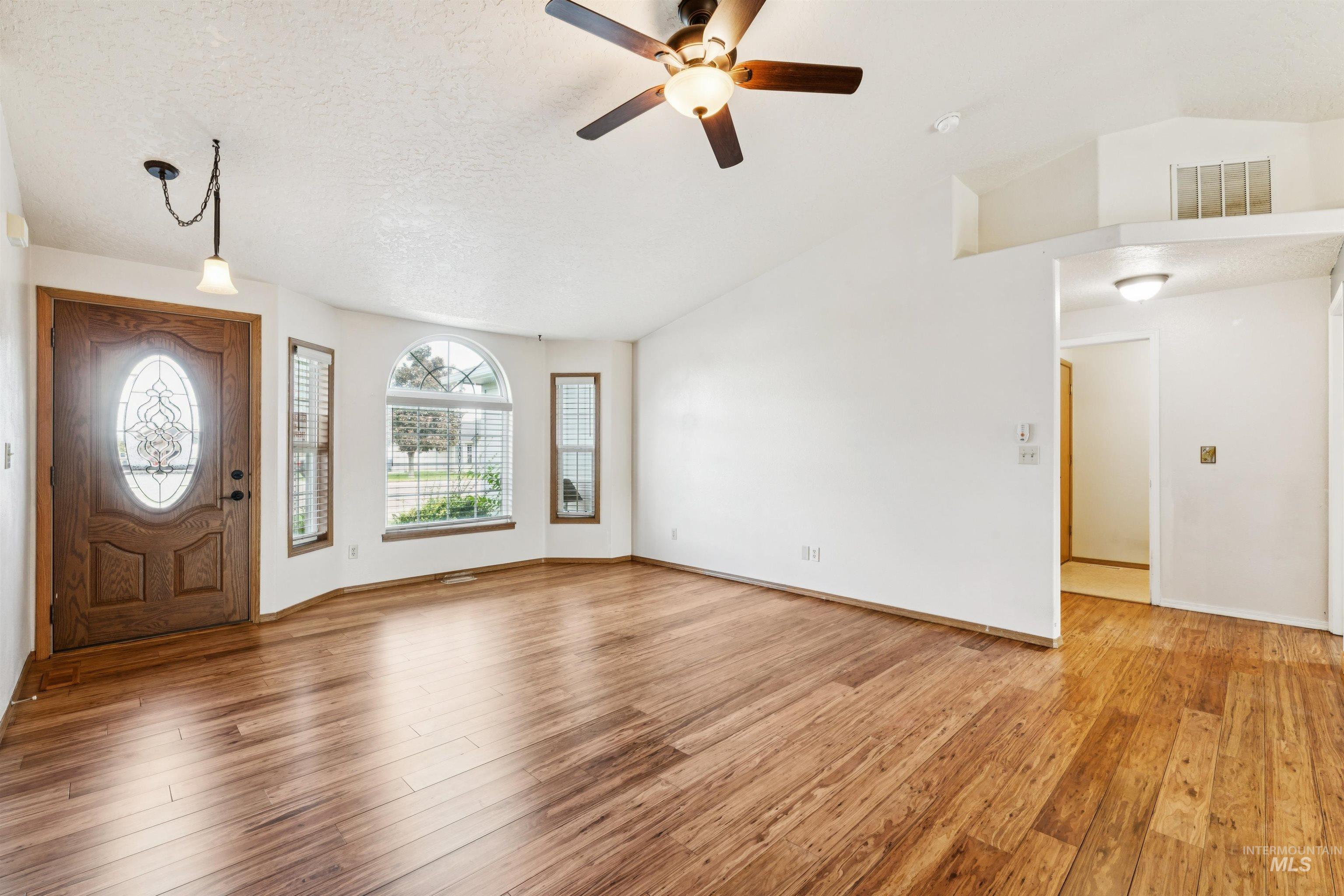 Foyer featuring light wood-style flooring, ceiling fan, a textured ceiling, and high vaulted ceiling
