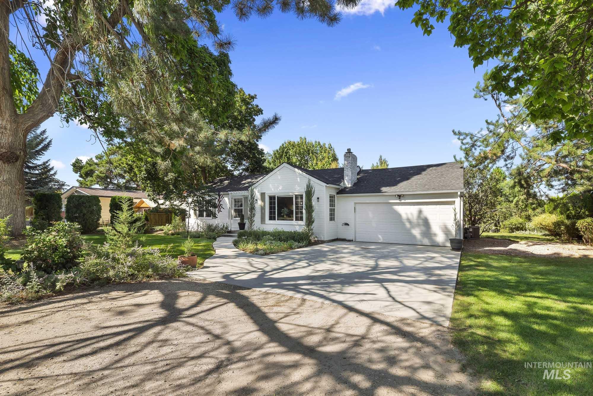 View of front facade featuring concrete driveway, a chimney, a garage, and a front lawn
