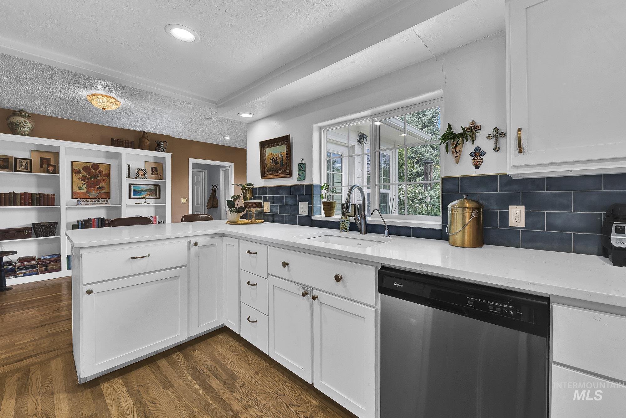 Kitchen featuring stainless steel dishwasher, recessed lighting, white cabinetry, hardwood flooring and a Quartz breakfast bar