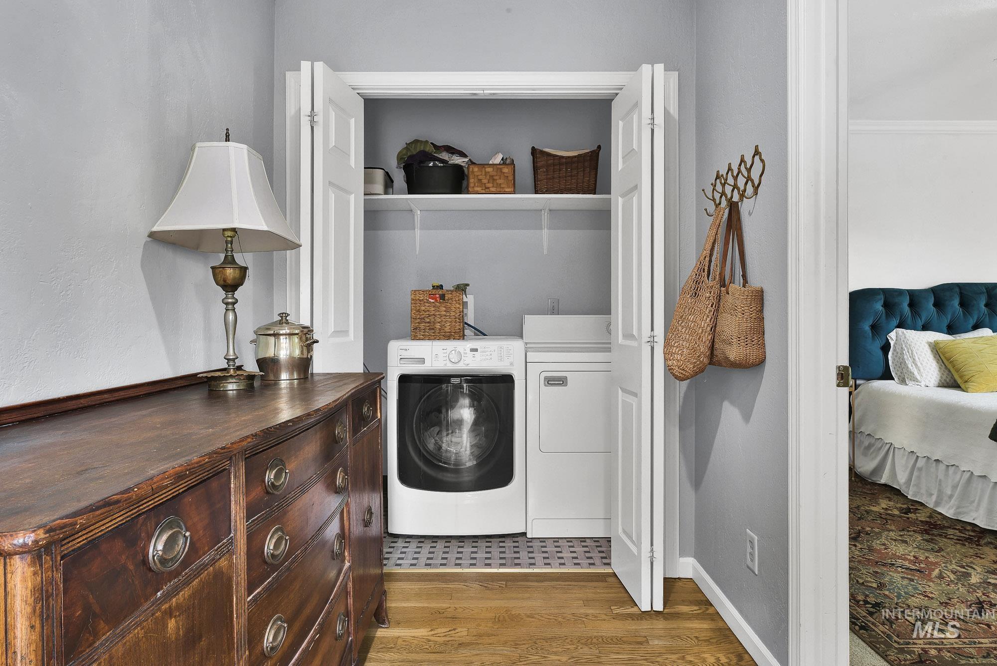 Enclosed laundry area  featuring hardwood finished floors, wide hallway and larger access doorway for the Primary Suite