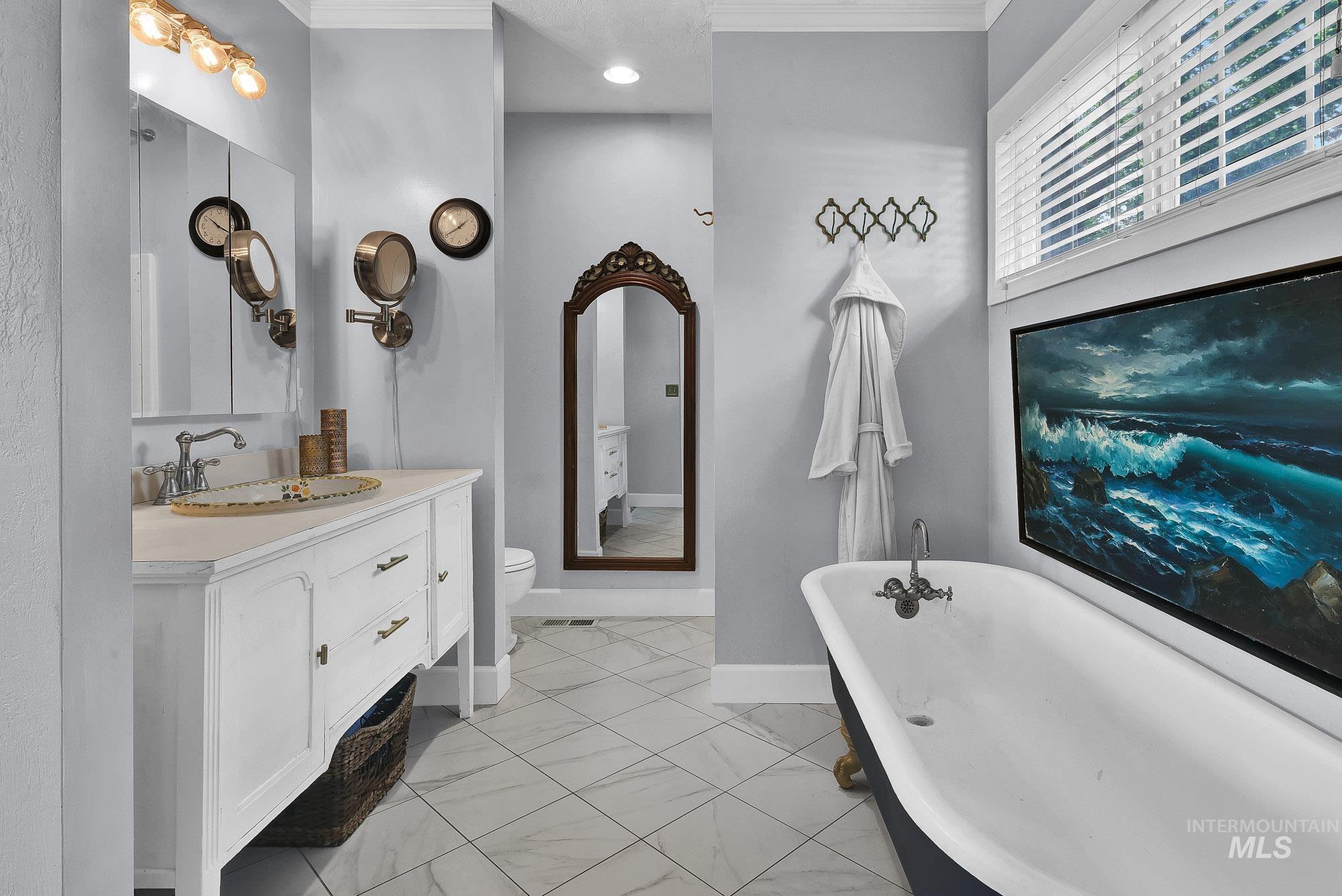 Full bath with a soaking tub, ornamental molding, vanity, and full tile flooring