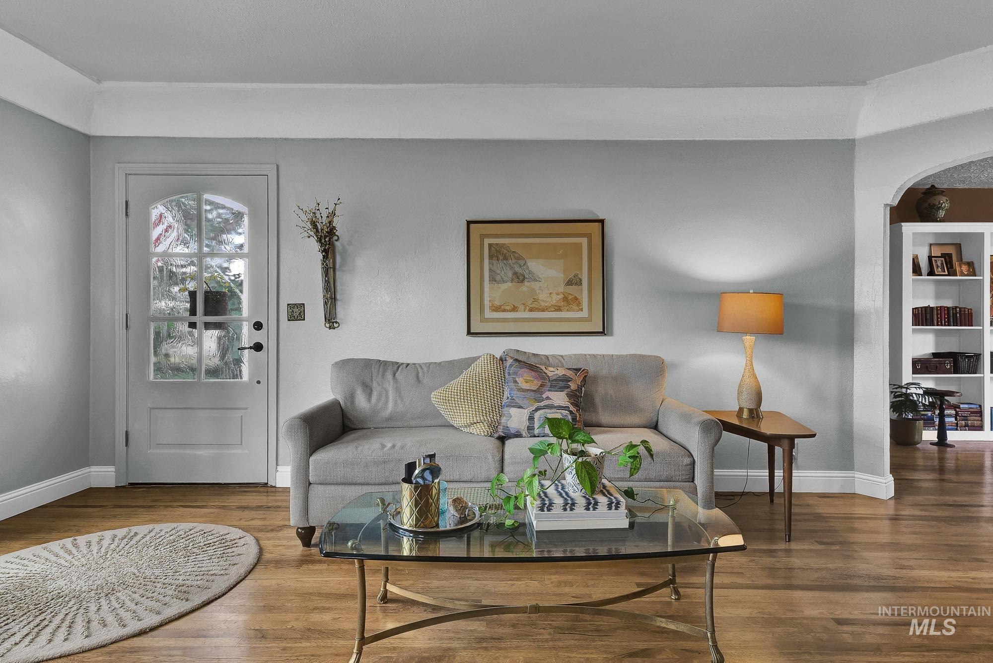 Living room featuring wood finished floors, arched walkways- coved ceiling and unique glassed front door