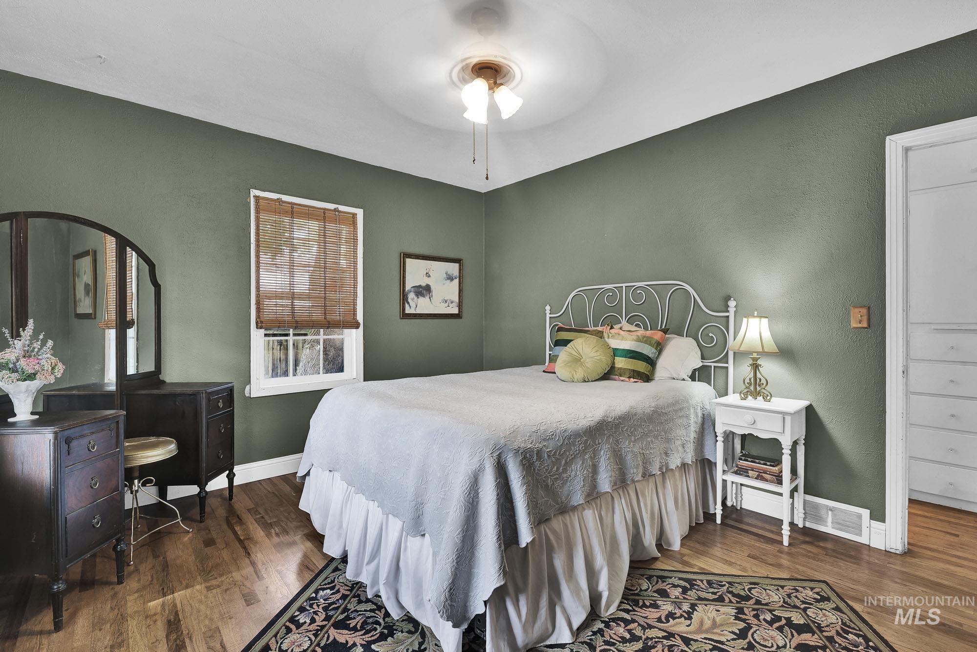 Bedroom with hardwood floors, a ceiling fan, and nice closet space