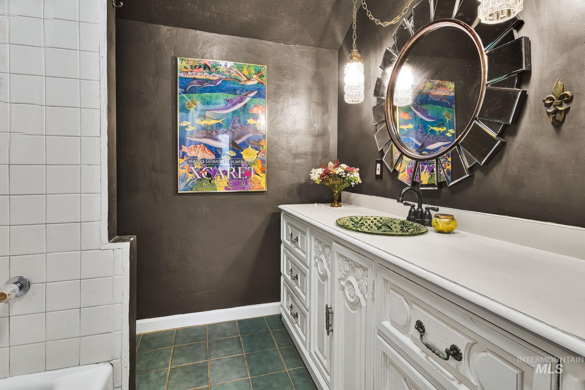 Bathroom featuring vanity, dark tile patterned flooring, and tub / shower combination