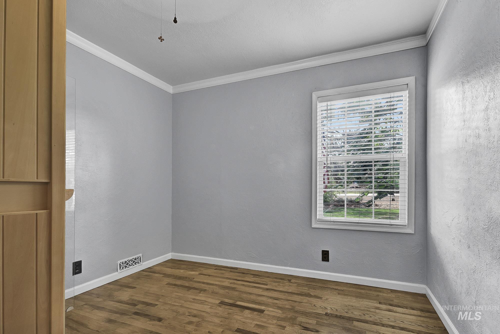 Bedroom with harwood flooring, crown molding, and a textured wall