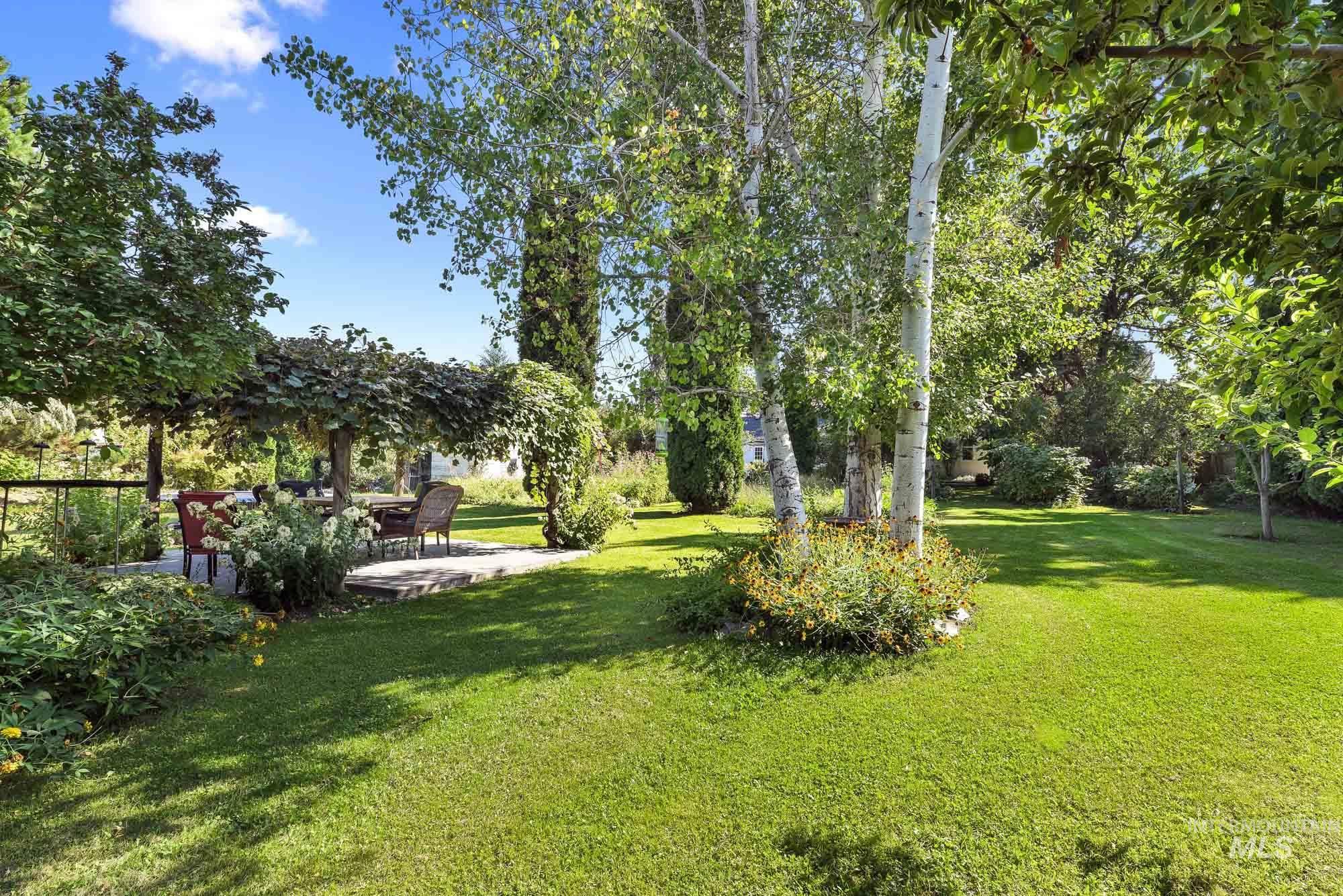 View of grassy yard with view of scattered trees and covered quiet picnic area