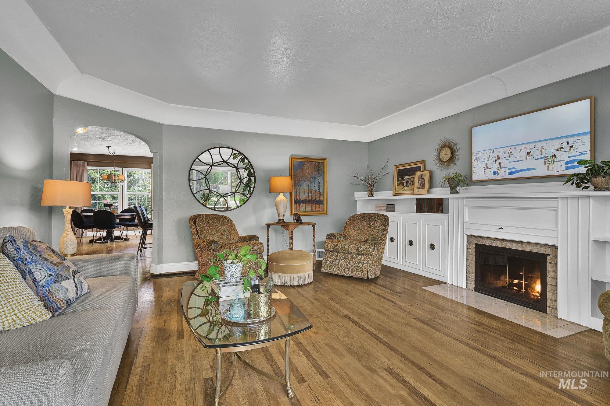 Living area with wood finished floors, a fireplace with flush hearth, arched walkways and coved ceiling